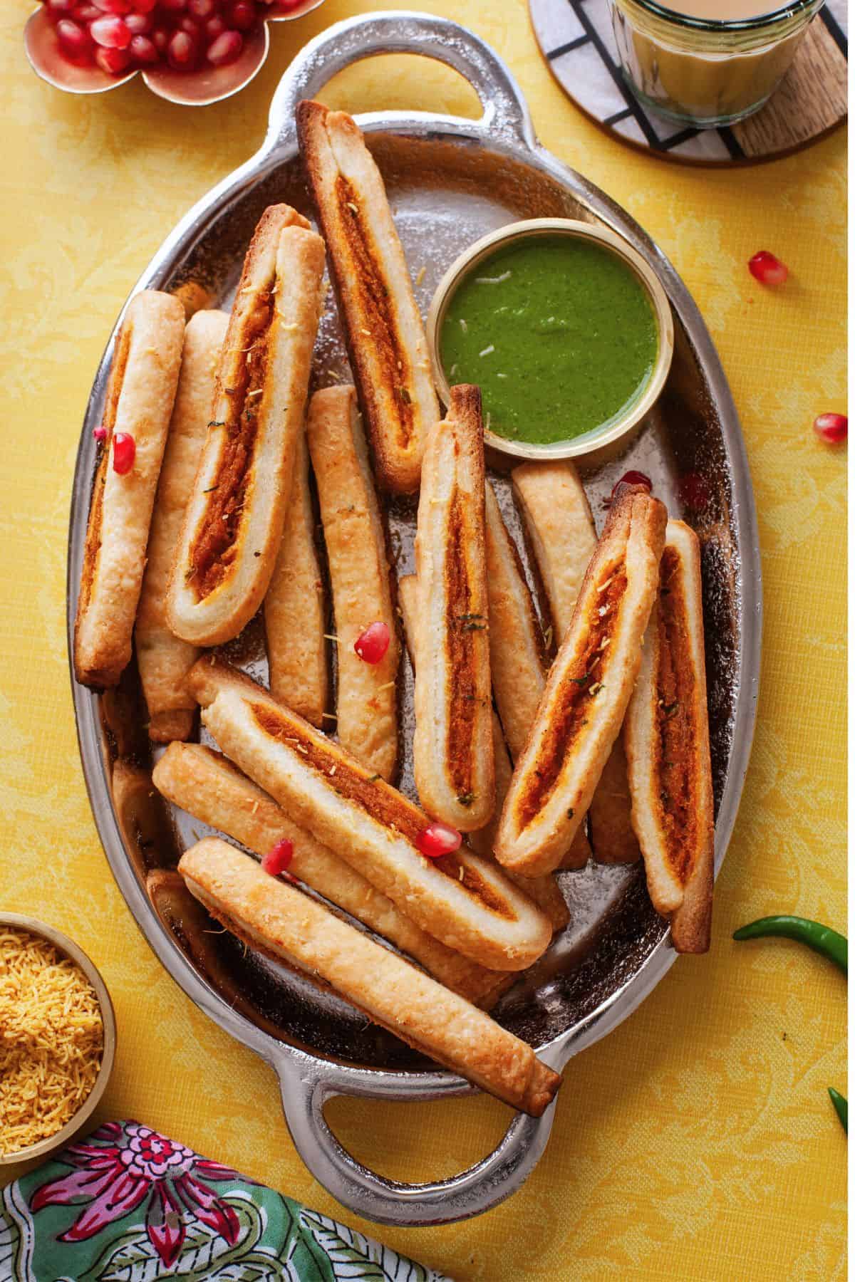Samosa sticks on an oval steel platter.