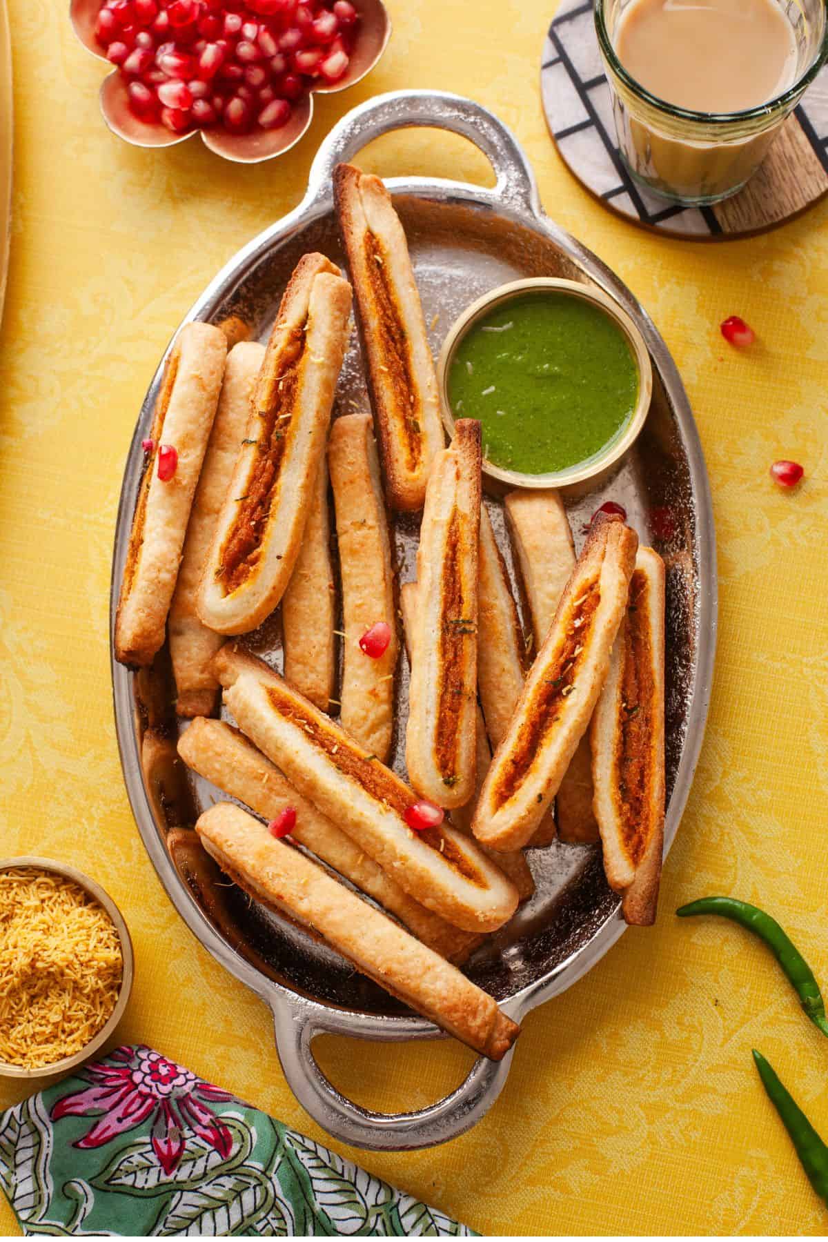 Samosa Sticks On an oval platter served with green chutney.
