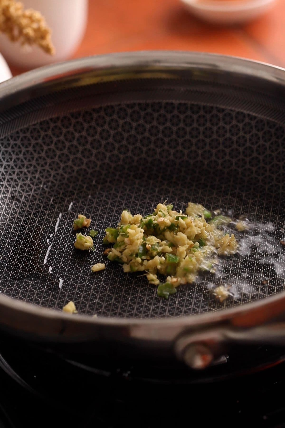 Minced ginger and green chillies are sizzling in oil.