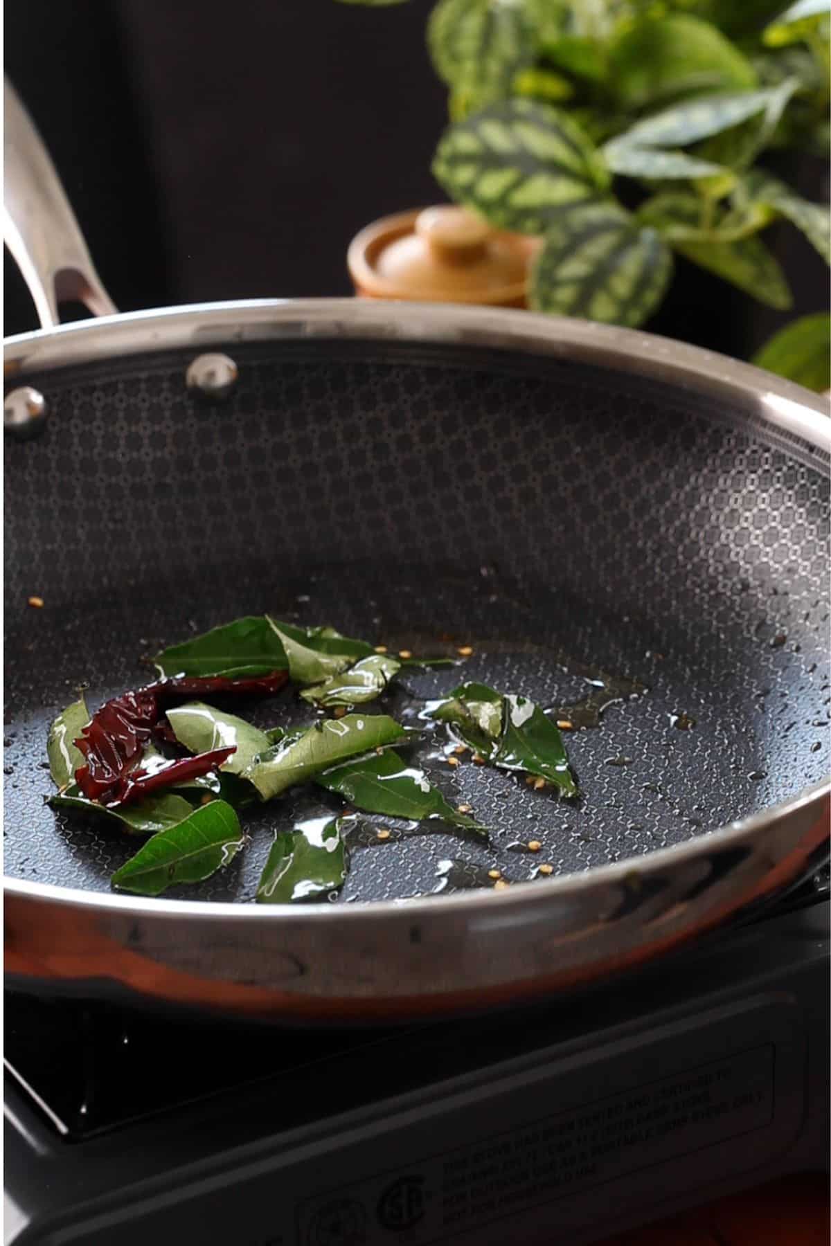 Curry leaves and dried chilies in hot oil.