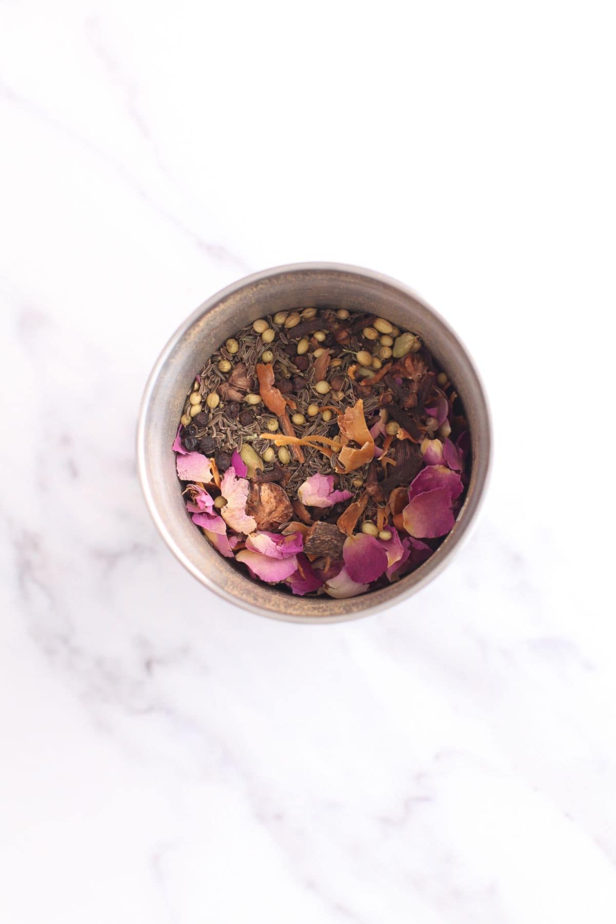 Toasted spices and rose petals are added to a small blender jar. 