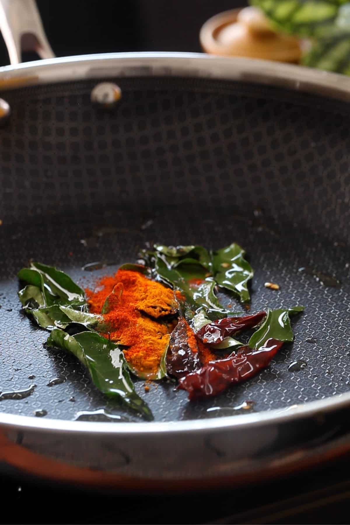 Ground spices are added next to the skillet.
