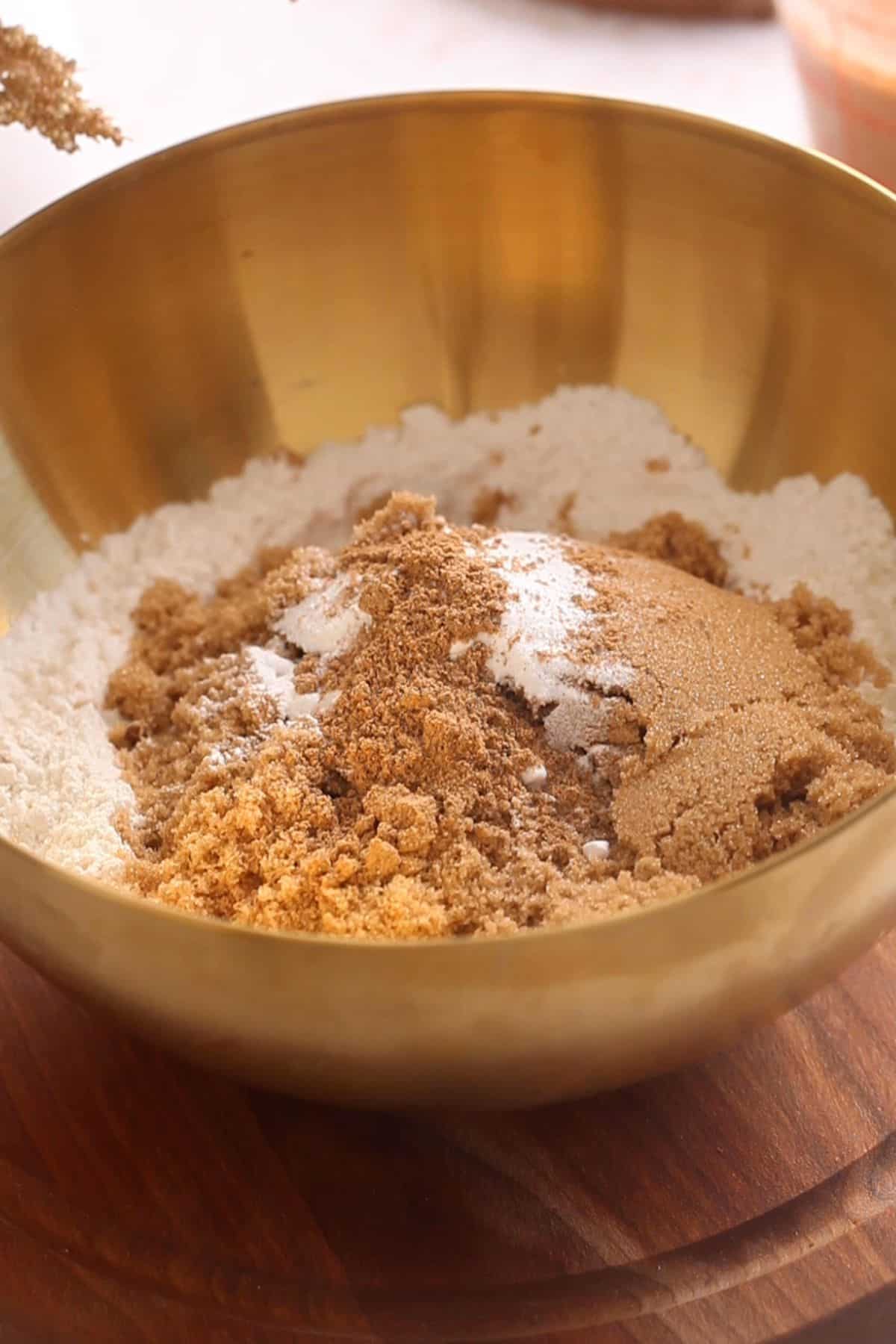 Dry ingredients in a gold mixing bowl for making chai cake.