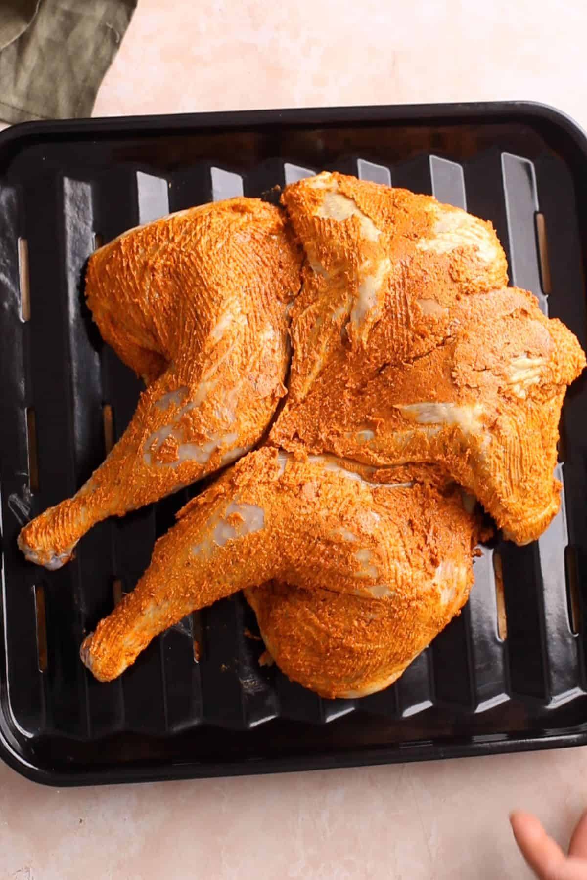 Marinated masala butter chicken is placed over a roasting rack. 