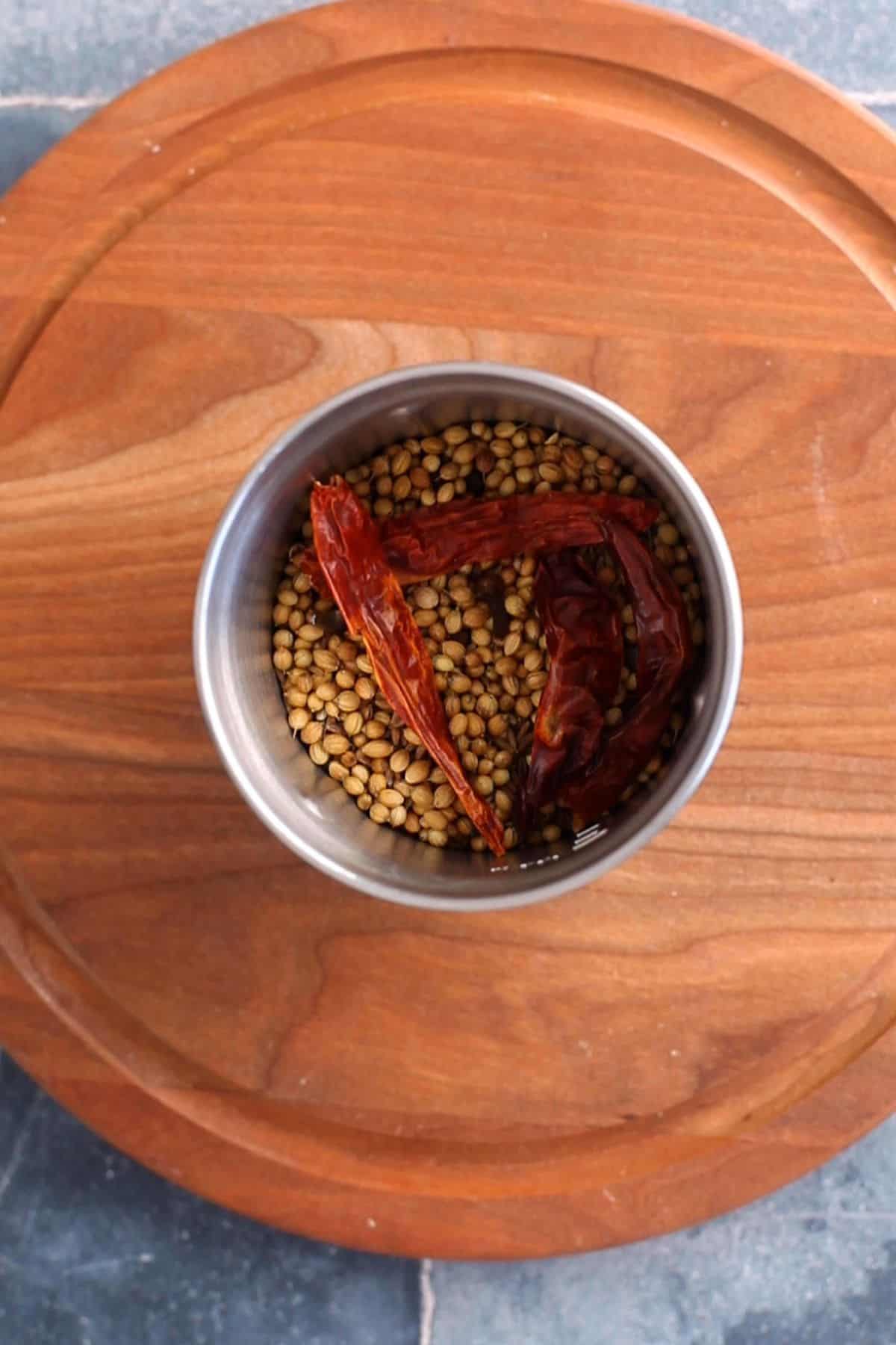 Roasted spices are placed in a steel grinder. 
