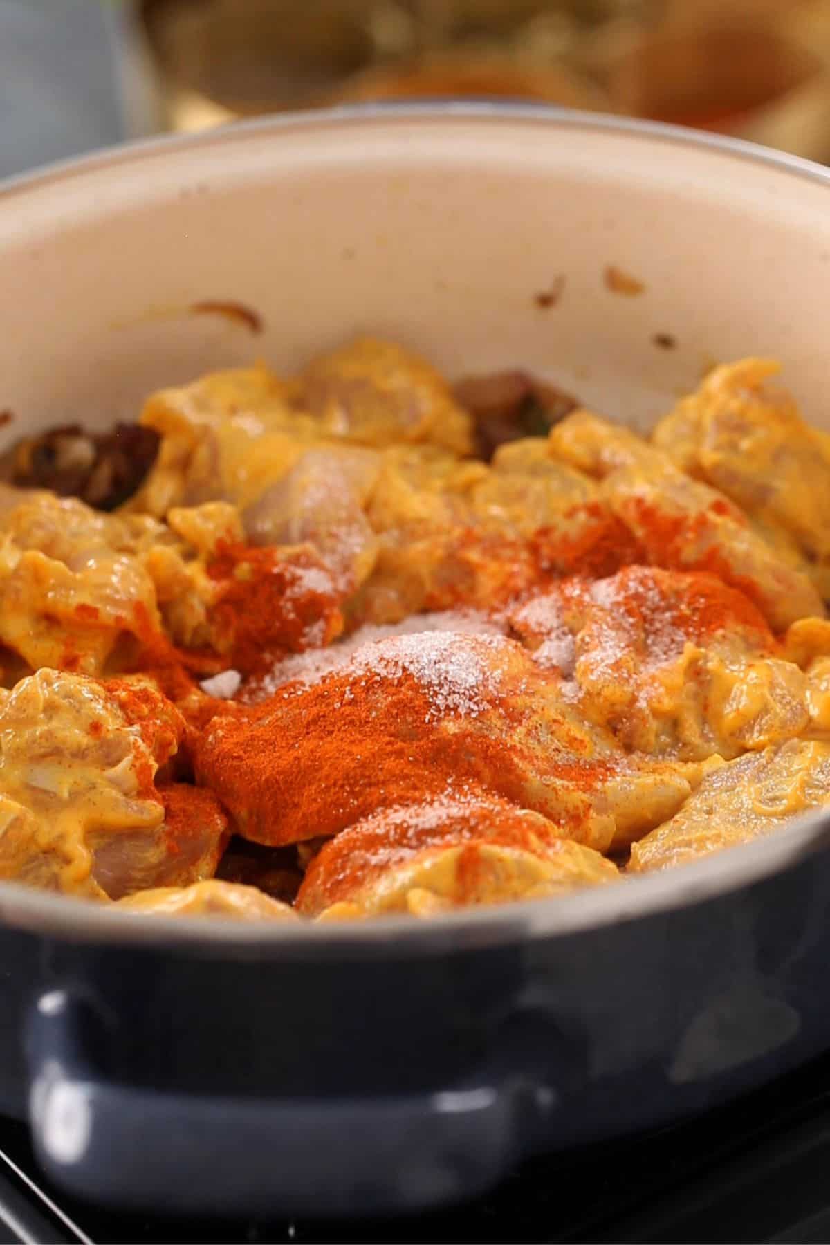 Marinated chicken is added to the cooking pot.