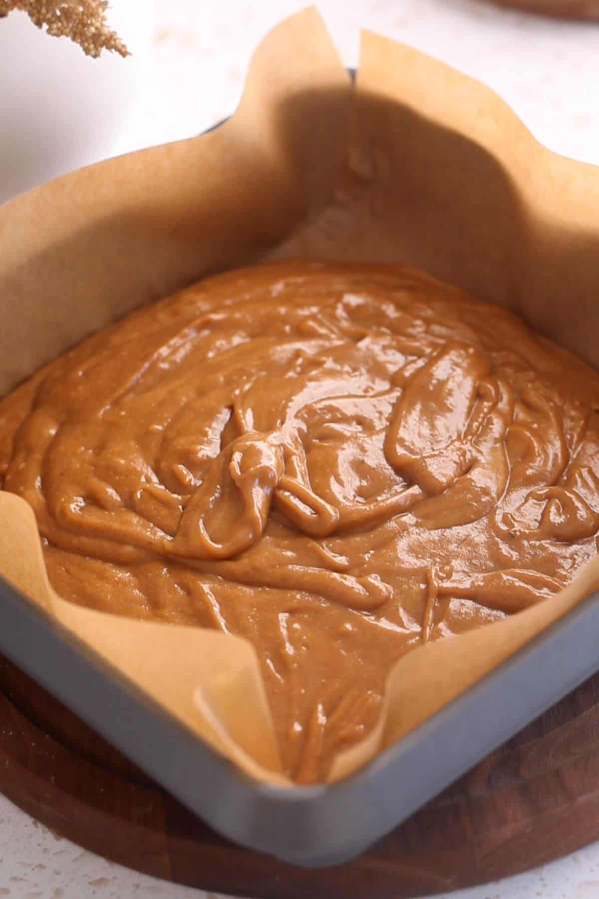 Cake batter is transferred to a brown parchment lined baking pan.