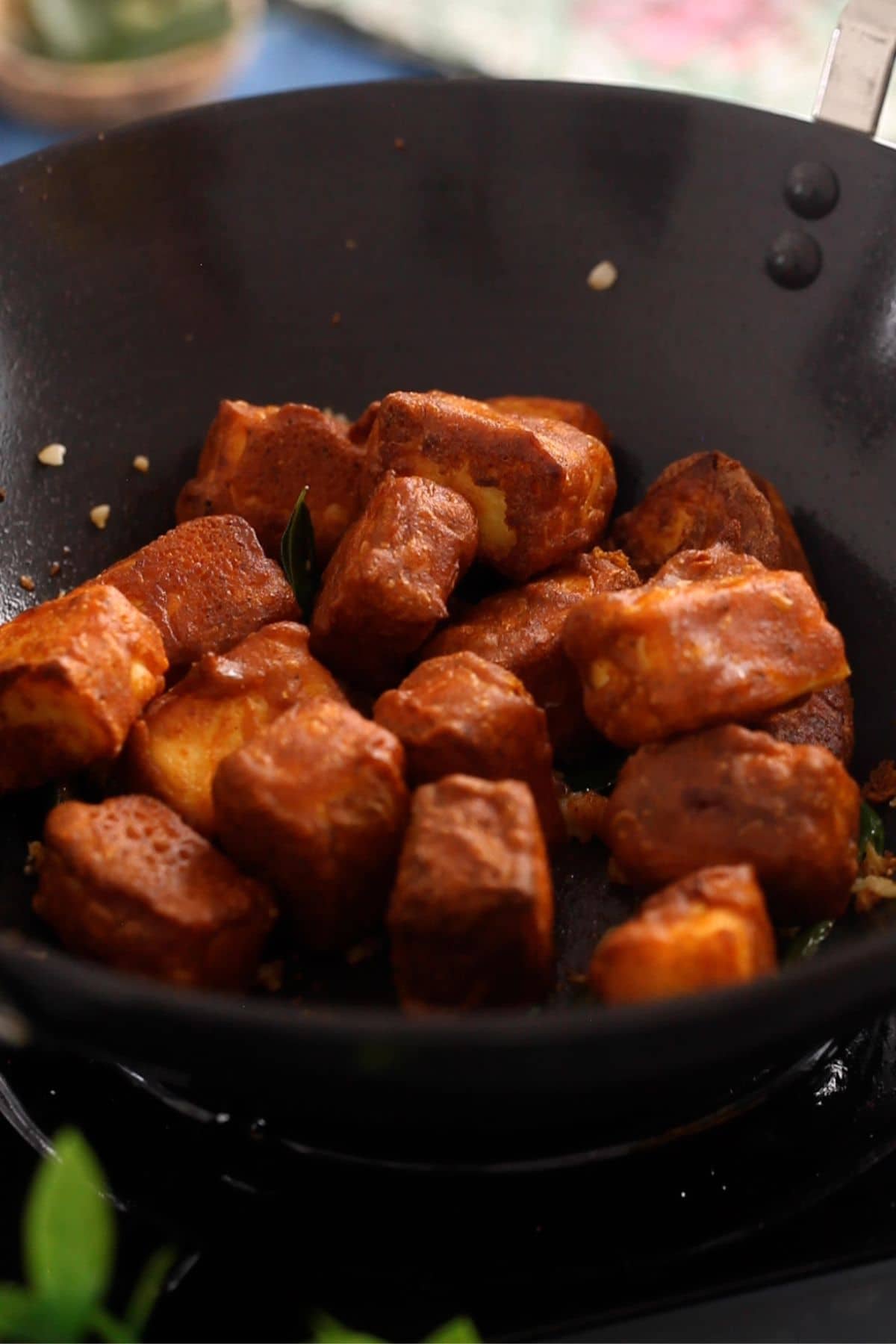 Fried pieces of paneer are added to the wok.