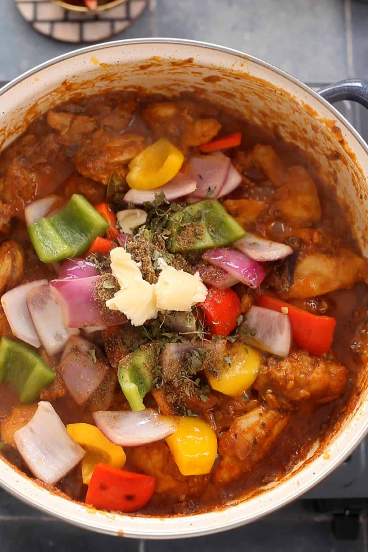 Bell peppers, ghee, finishing spices and onions are added to the kadai.