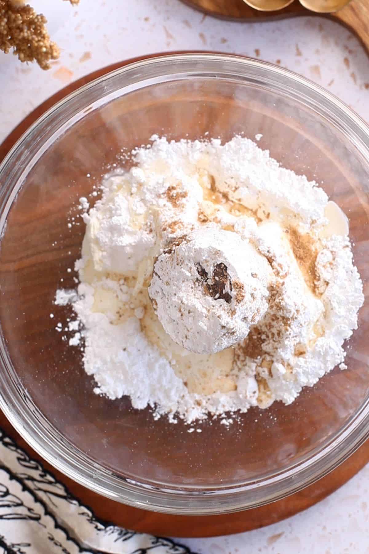 Ingredients for cream cheese frosting are added to a glass bowl.