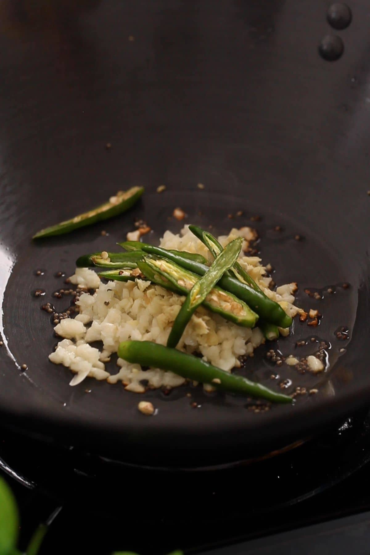 Oil is tempered with garlic, mustard seeds and green chilies.