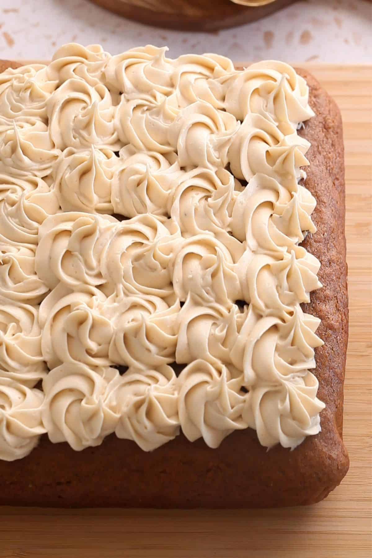 Chai cake is piped with cream cheese frosting.