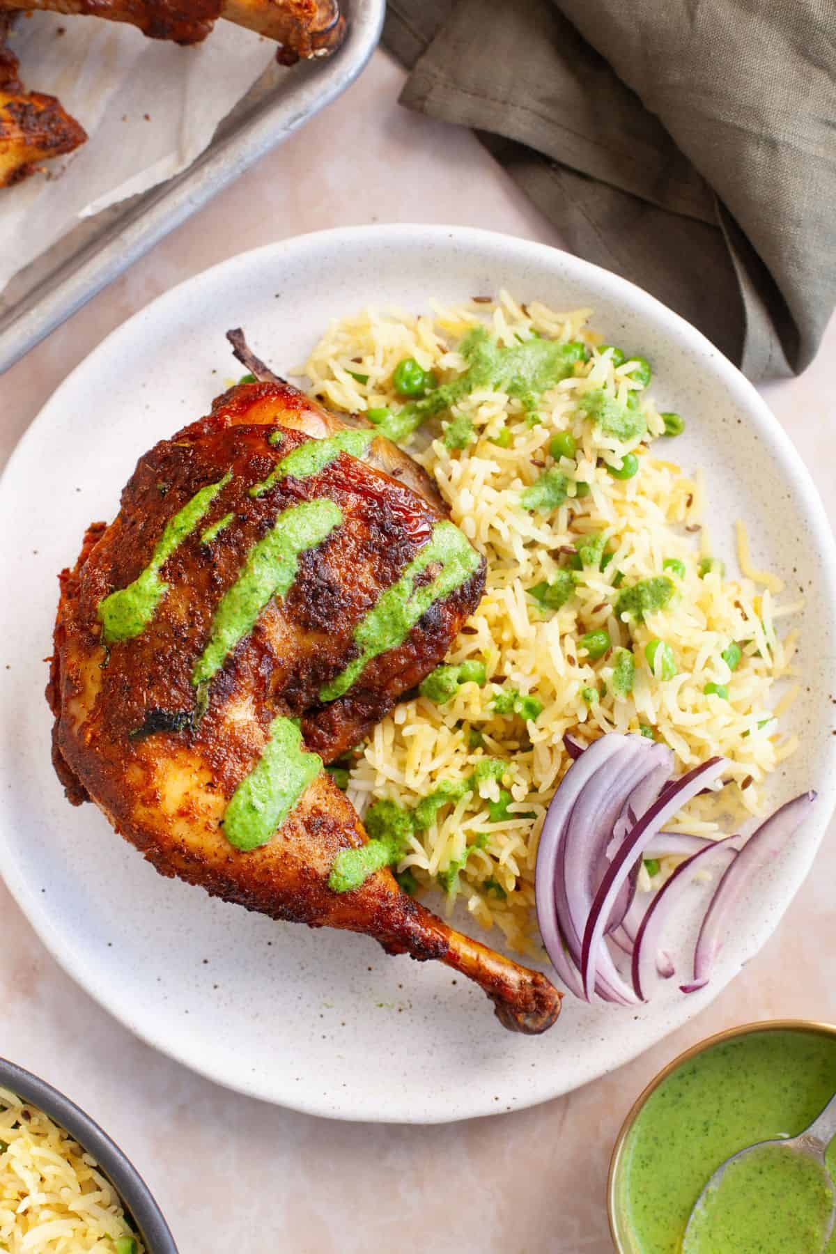 Carved leg quater from indian roast chicken served with peas pilaf and a drizzle of cilantro green chutney.