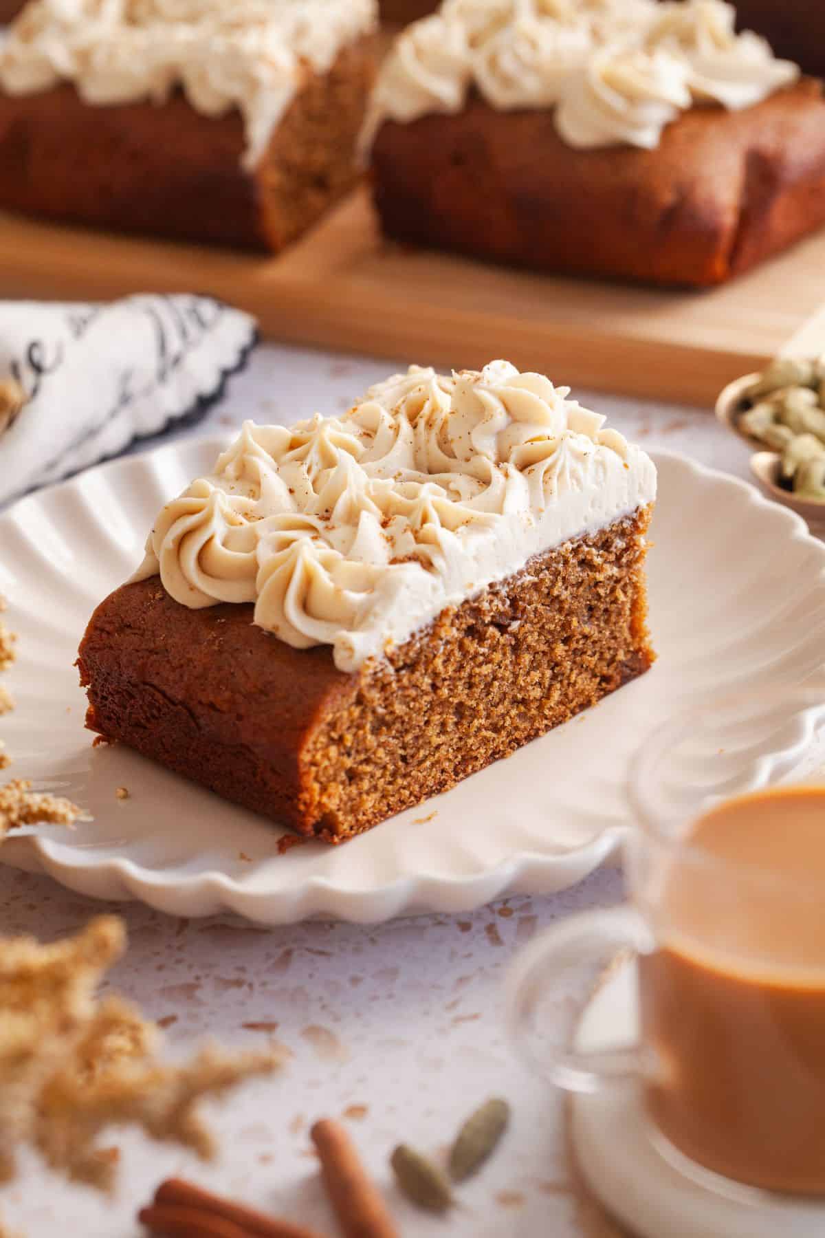 Front view of a chai spiced cake slice served on a fluted white plate.