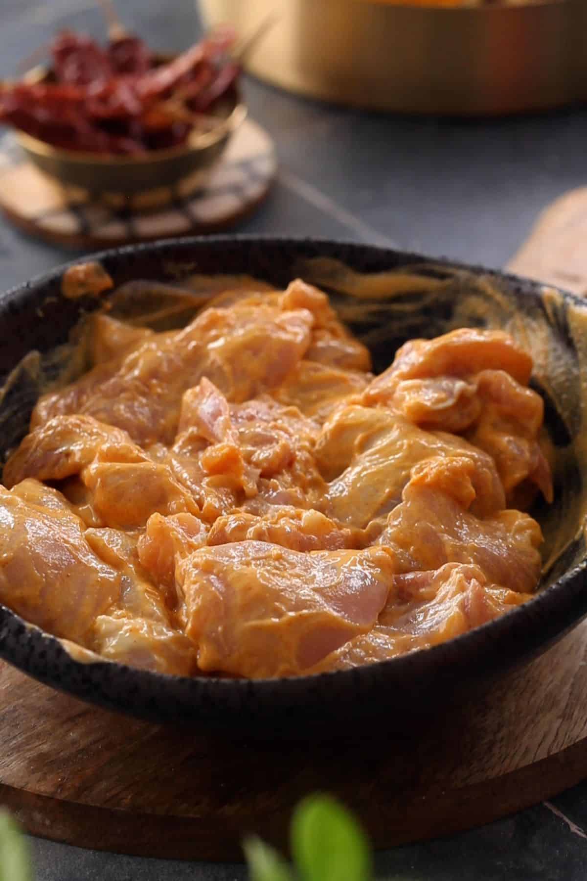 Marinated chicken in a black bowl.