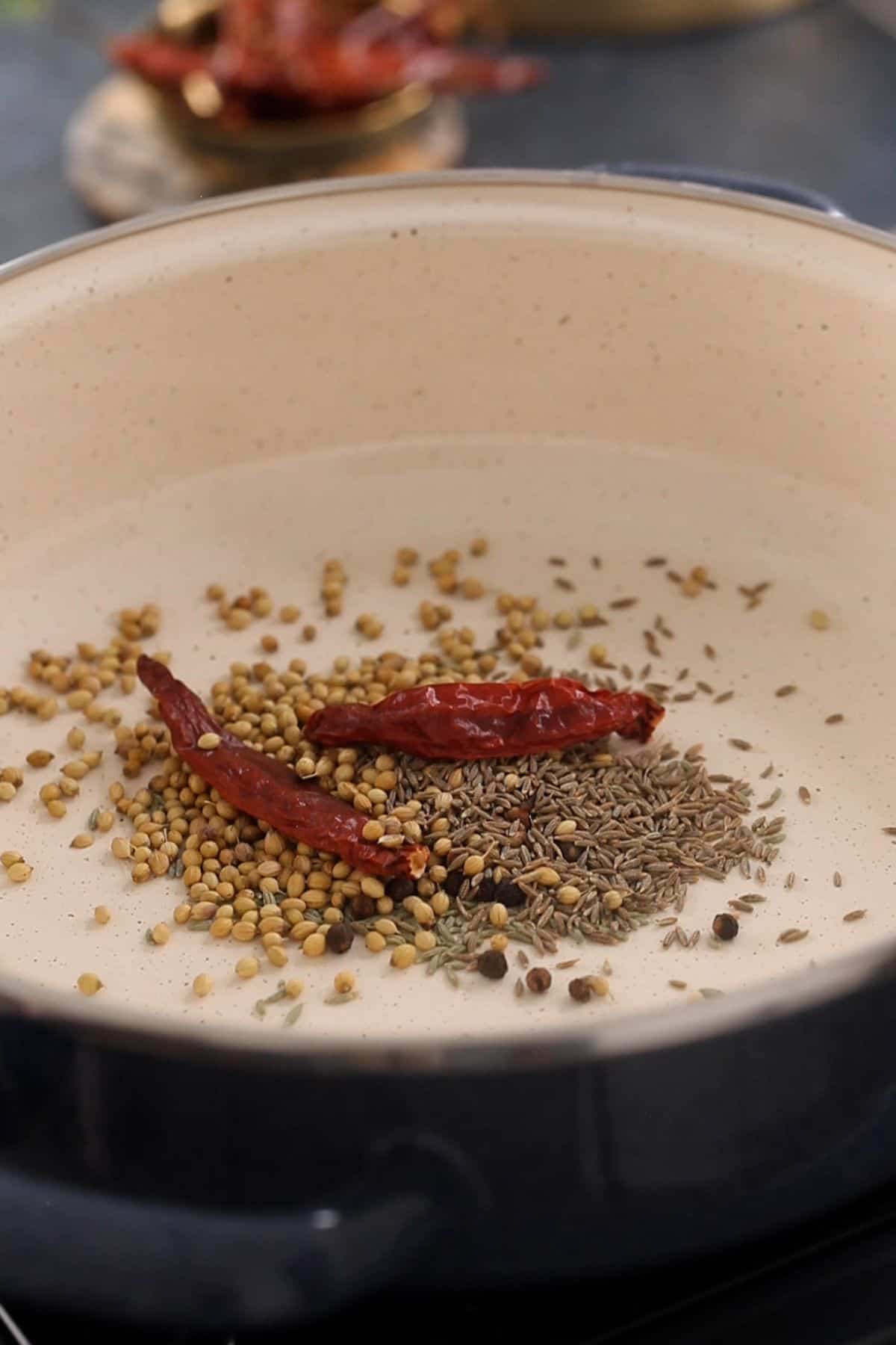 Dry roasting kadai spices in a cooking pot.