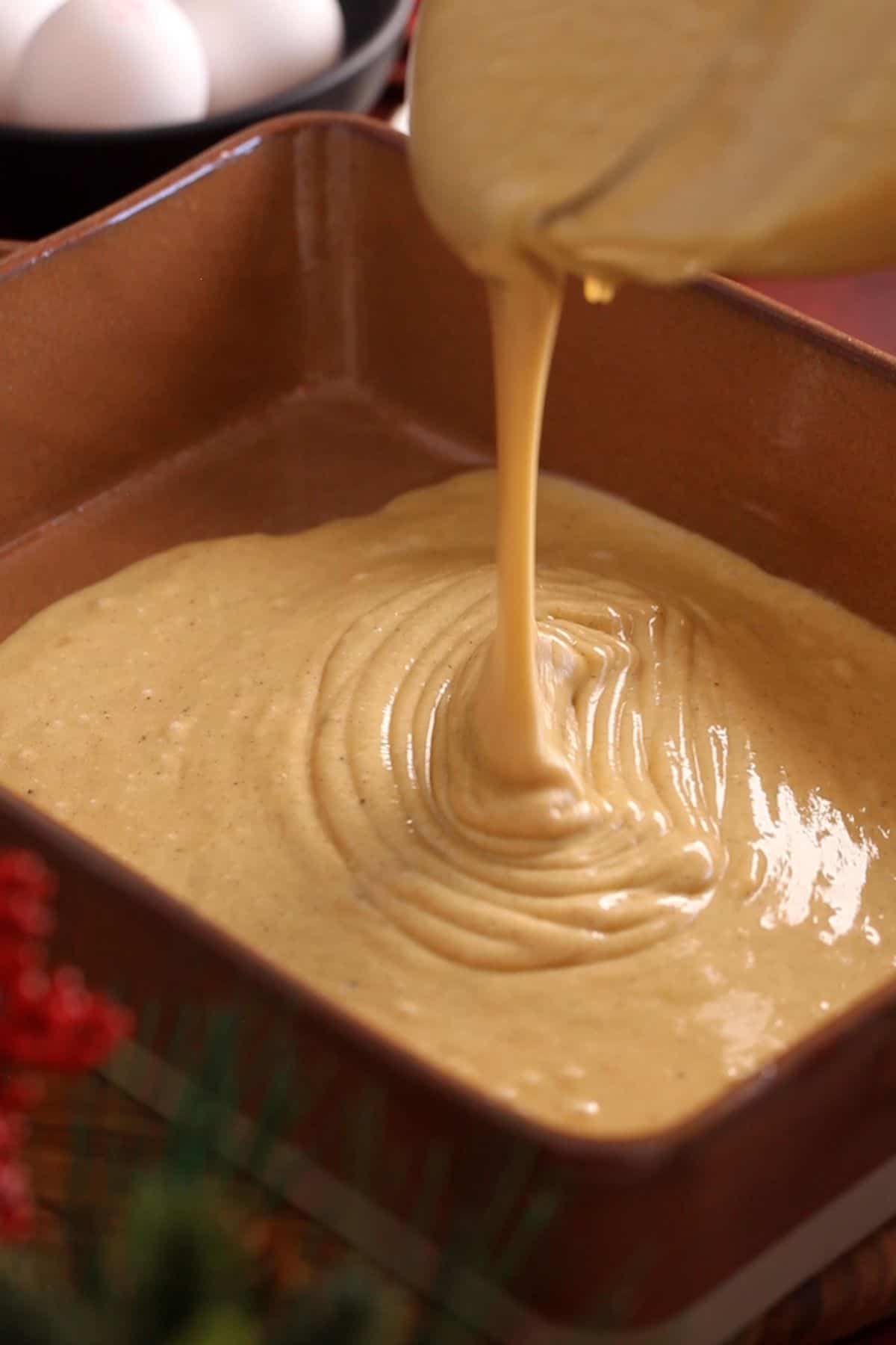 Pouring cake batter to a 9 by 13 brown colored baking dish.