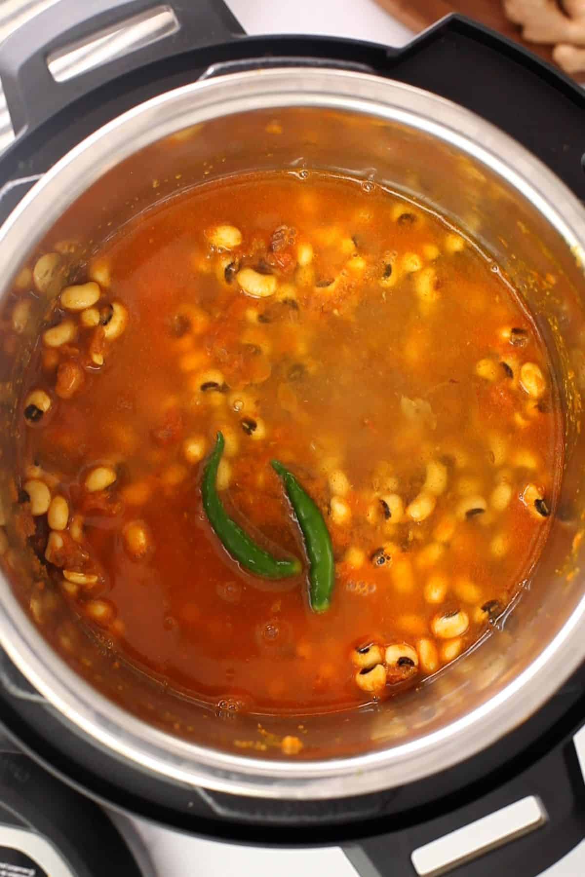 Water and green chilies are added to pressure cook the lobia. 