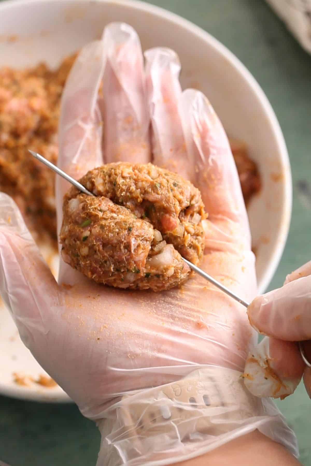 Metal skewer is inserted in the kebab mixture.