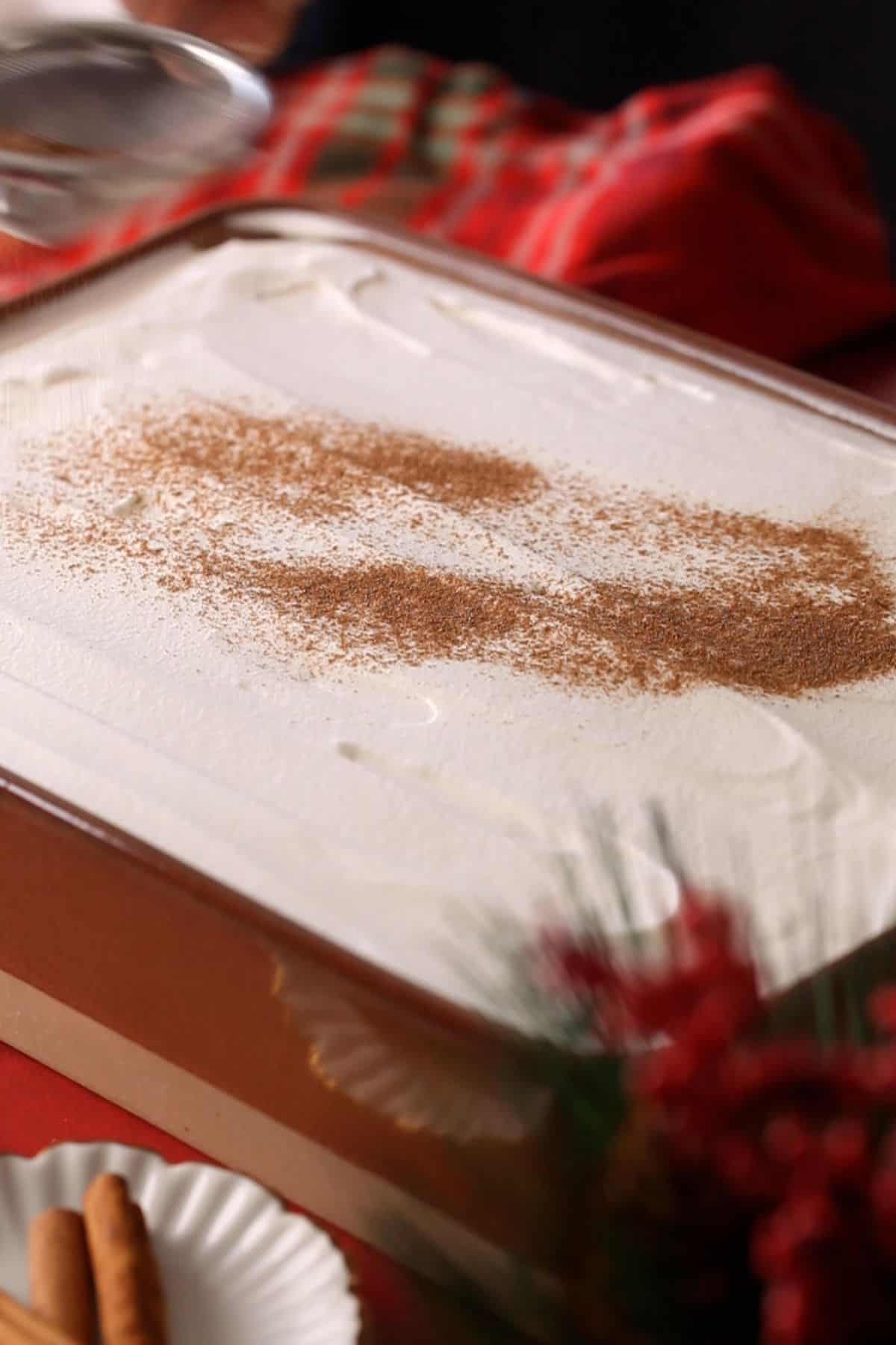 Ginger bread tres leches cake is topped with whipped cream and dusted with spices.