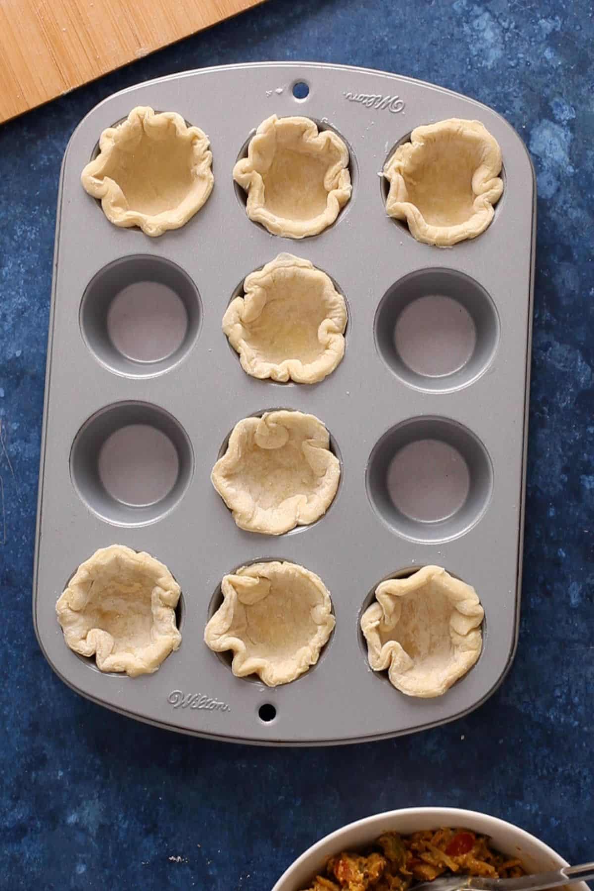Pastry rounds are put into muffin pan to create a small tart shell.