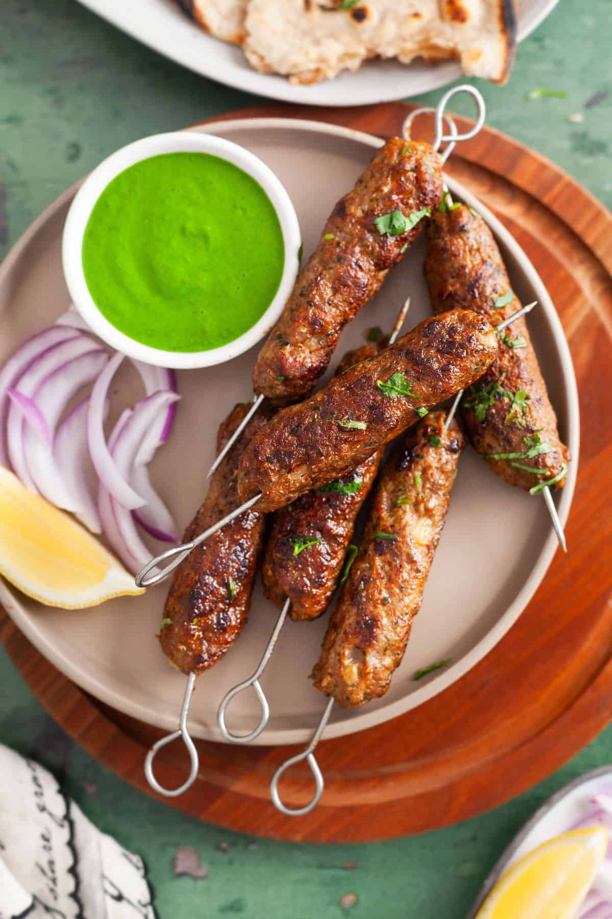 Lamb Seekh Kebab Served in a brown plate with green chutney.