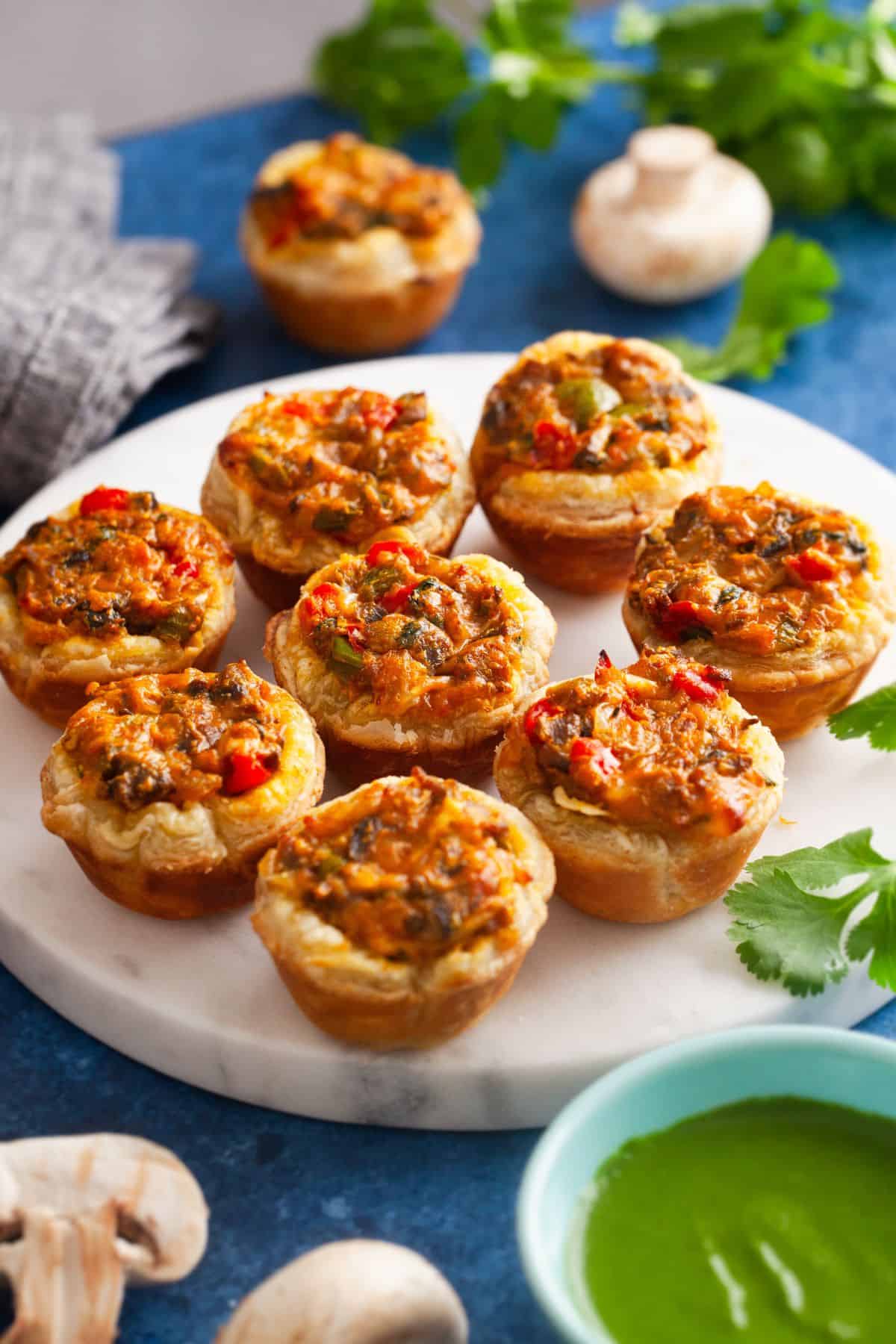 Masala Mushroom tartlets served on a white marble background with green chutney.