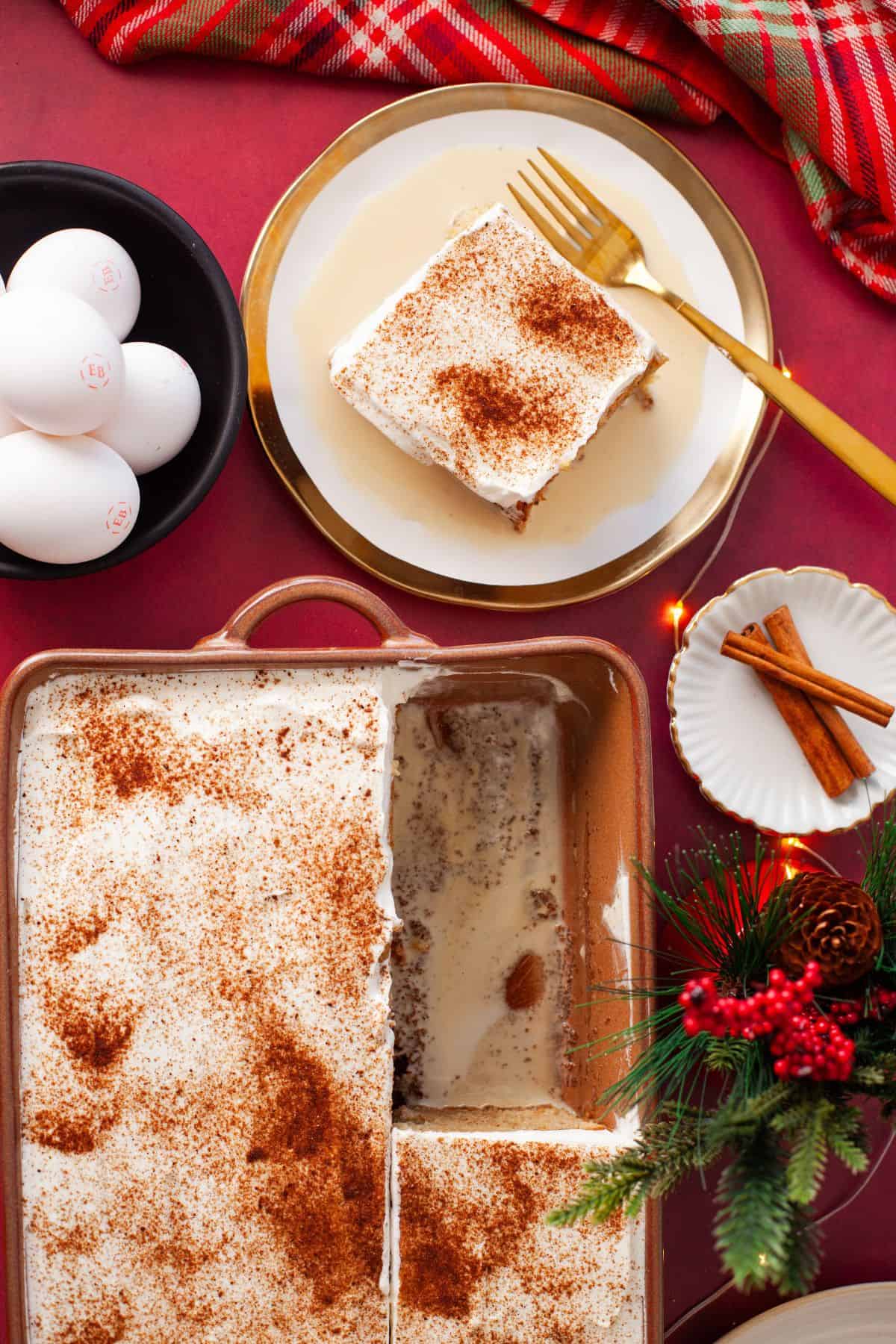 Ovehead image of ginger bread tres leches cake with a cake sliced from the whole cake in holiday table setting.