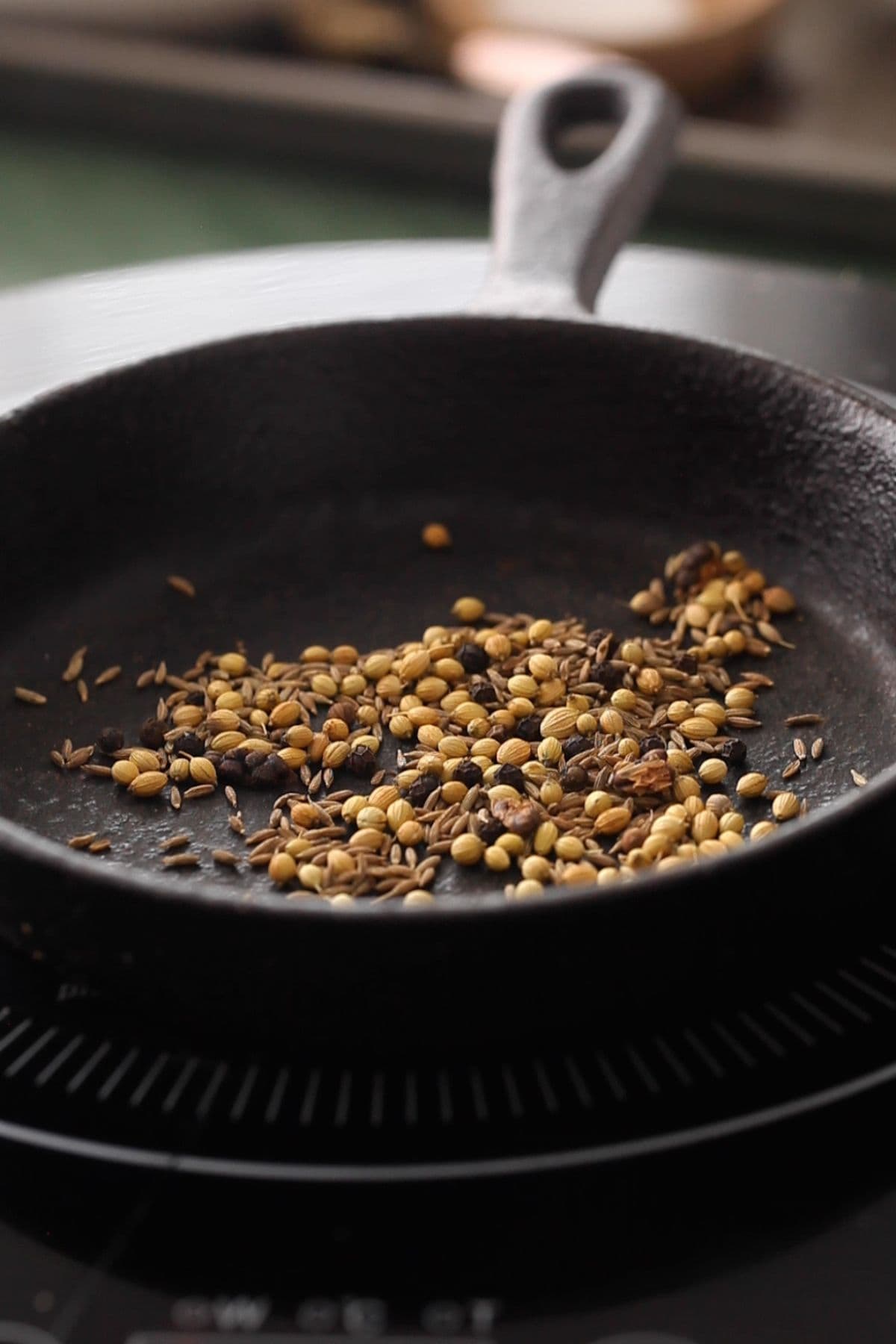 Whole spices roasted in a black skillet.