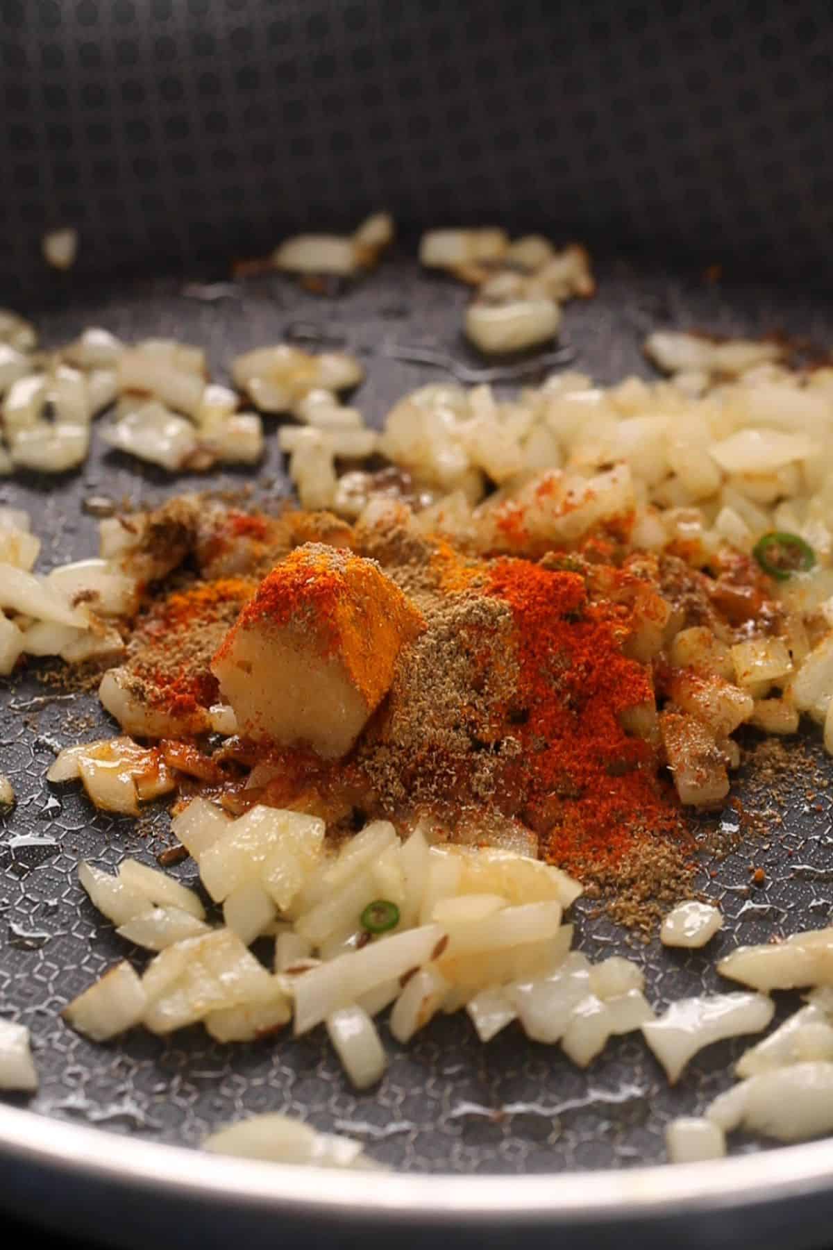 Ground spices, green chilies and garlic paste are added to the onions.