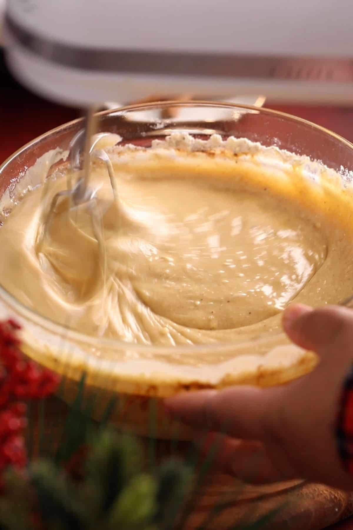 Cake batter is beaten using a hand held mixer.