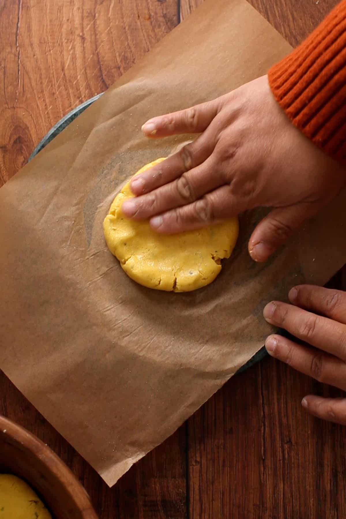 Spreading makki dough with hands to make a roti.