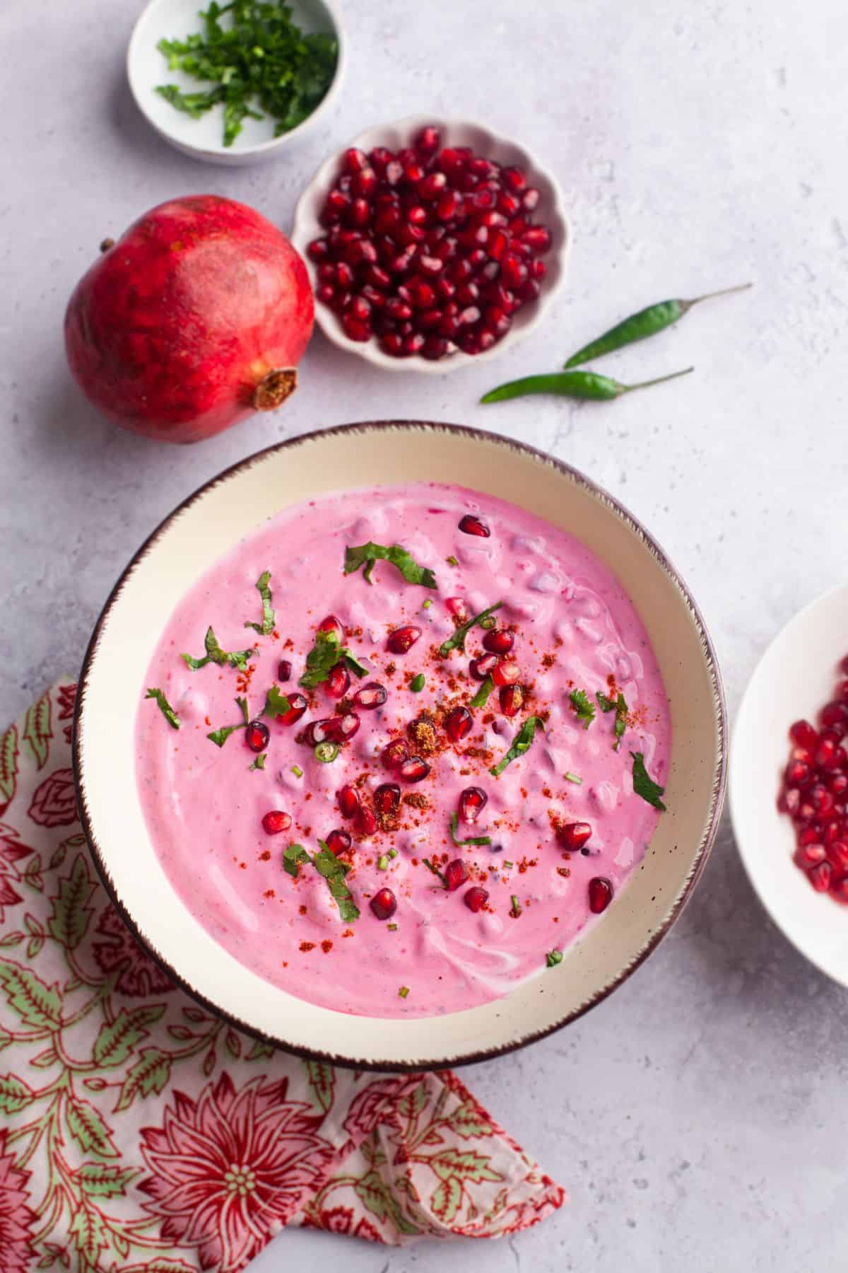 Anar raita served in a bowl sprinked with spices and cilantro.