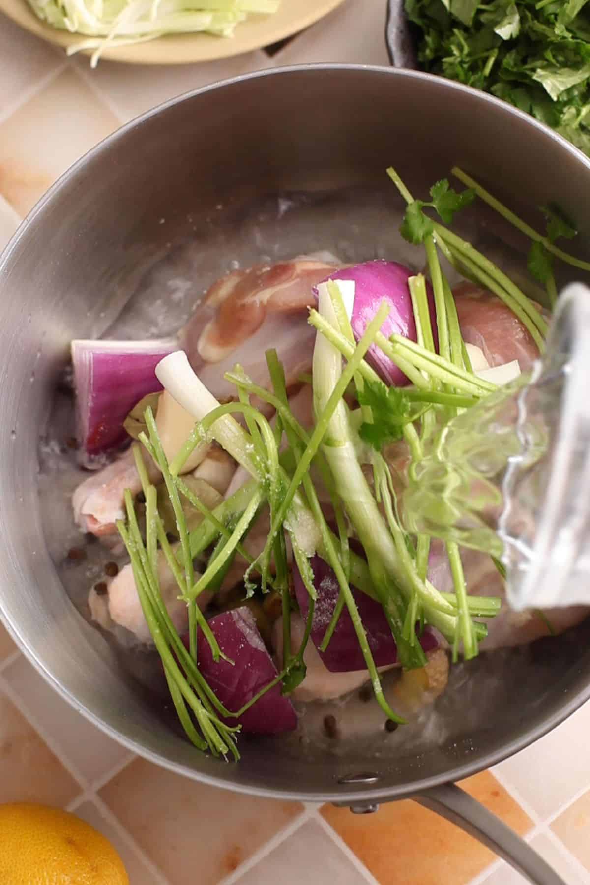 Ingredients for making chicken broth are placed in a steel pot.