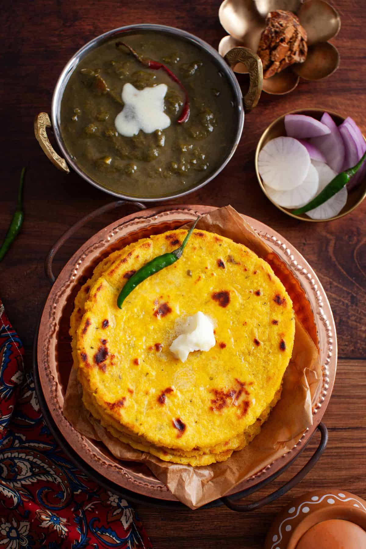Top view of a stack of makki roti served with a dollop of butter. 