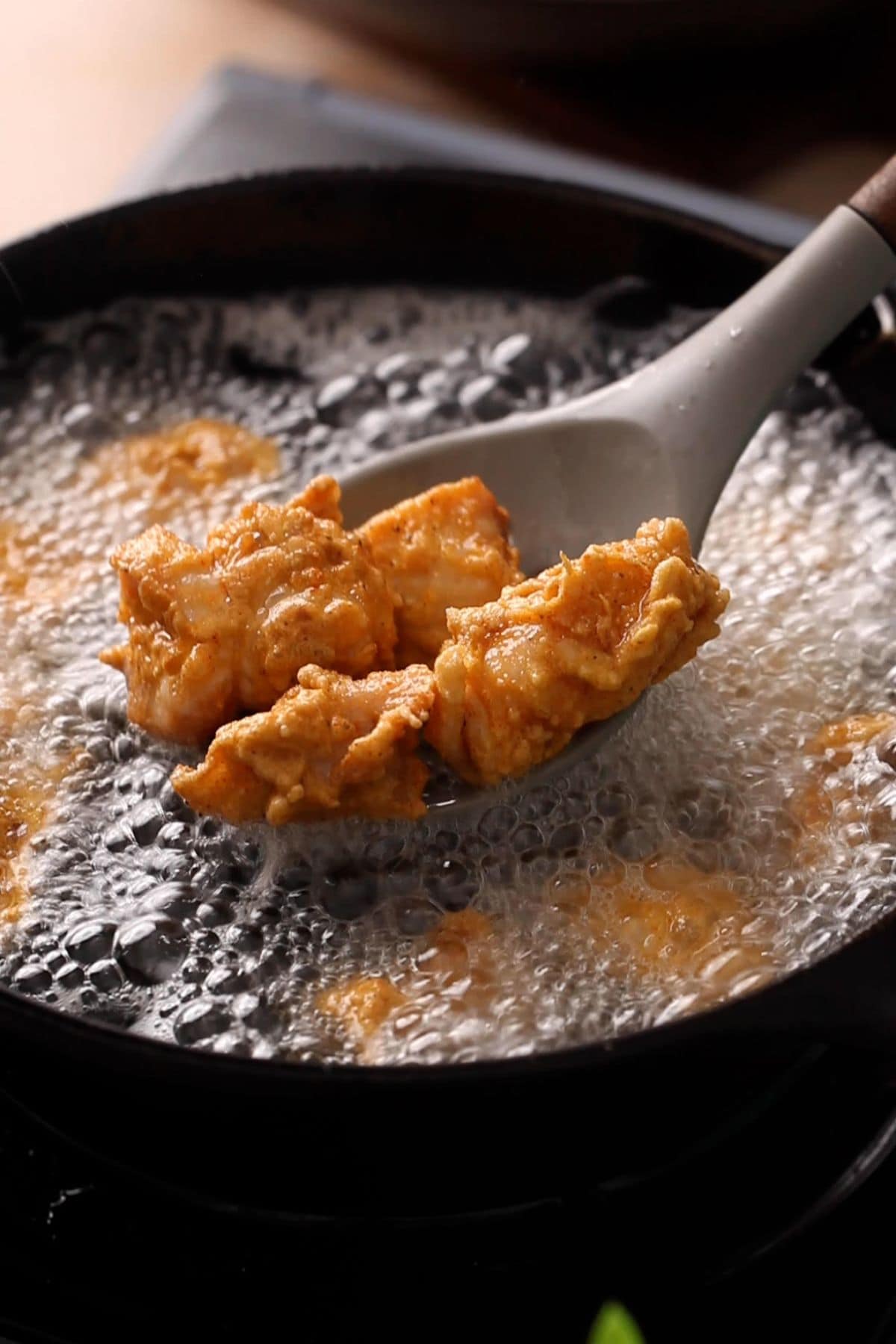 Chicken is lifted using a slotten spoon.