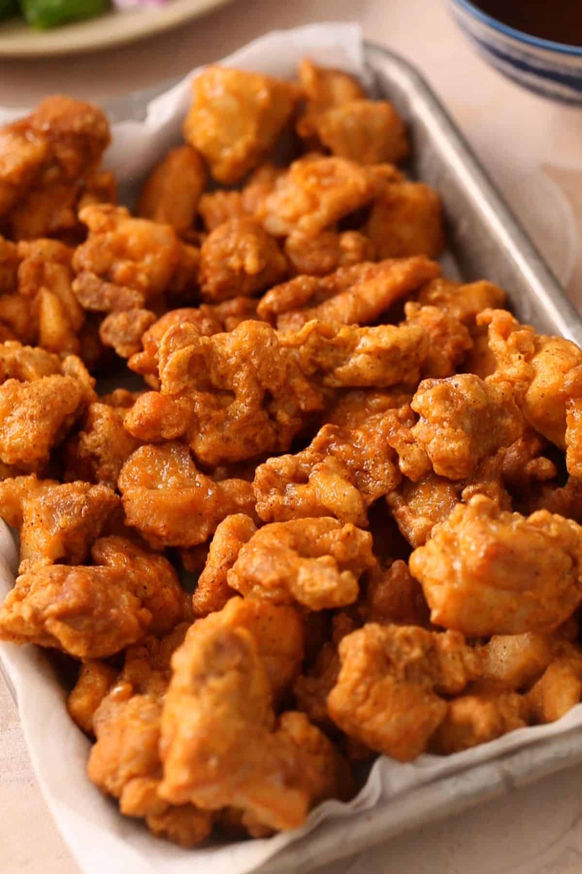 Crispy deep fried chicken is drained on paper towel. 