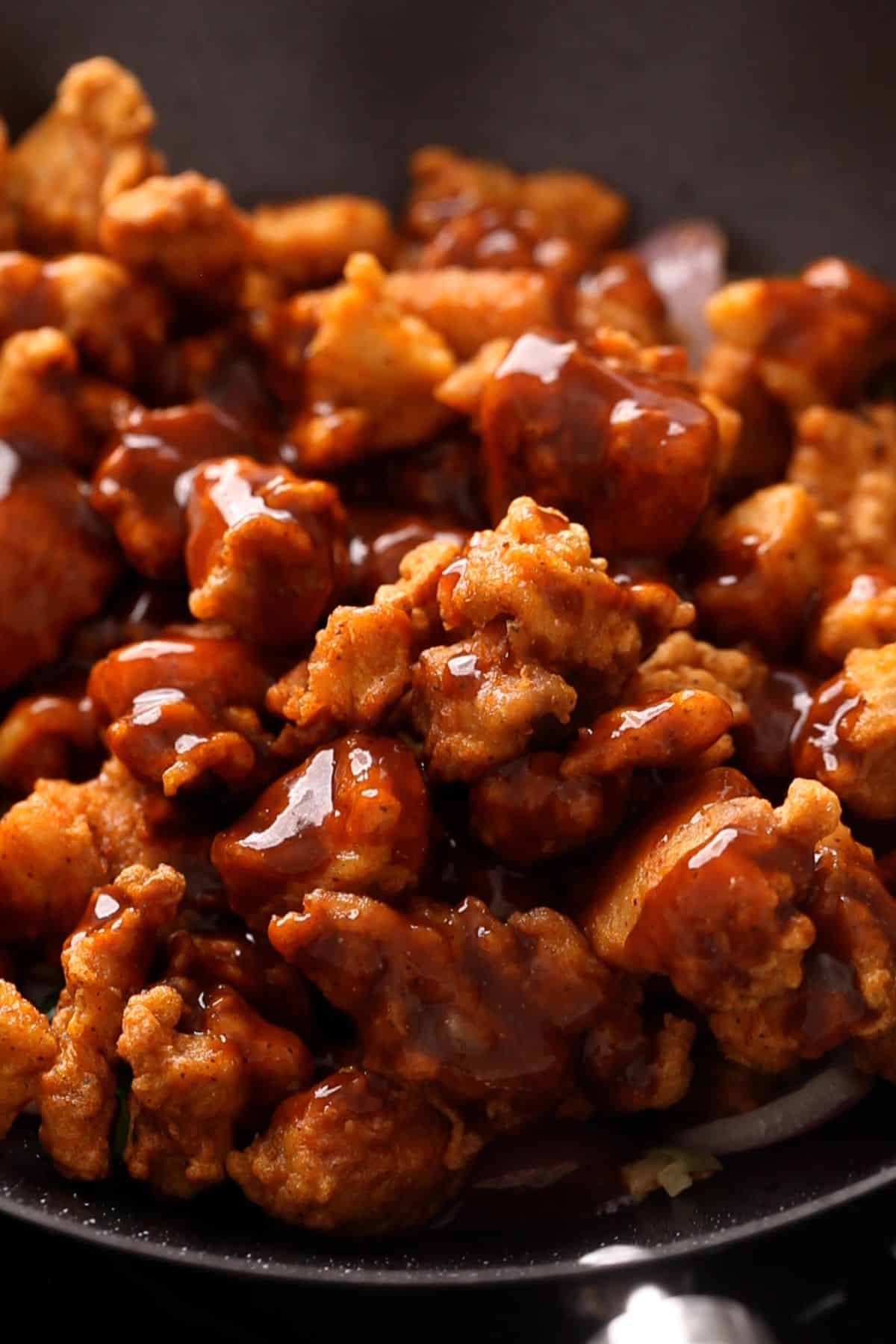 Fried chicen and sauce is added to the wok.