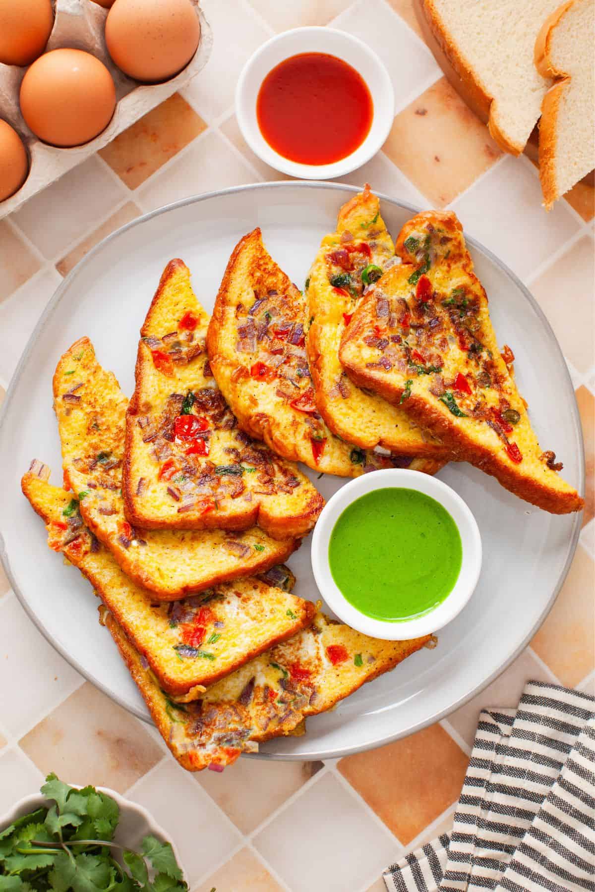 Indian french toast served on a white plate with green chutney.