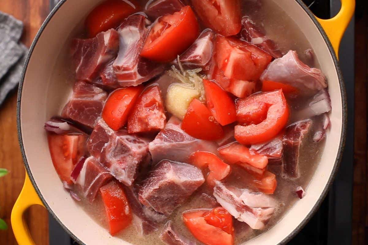 Goat meat is added along with tomatoes. ginger garlic and water.