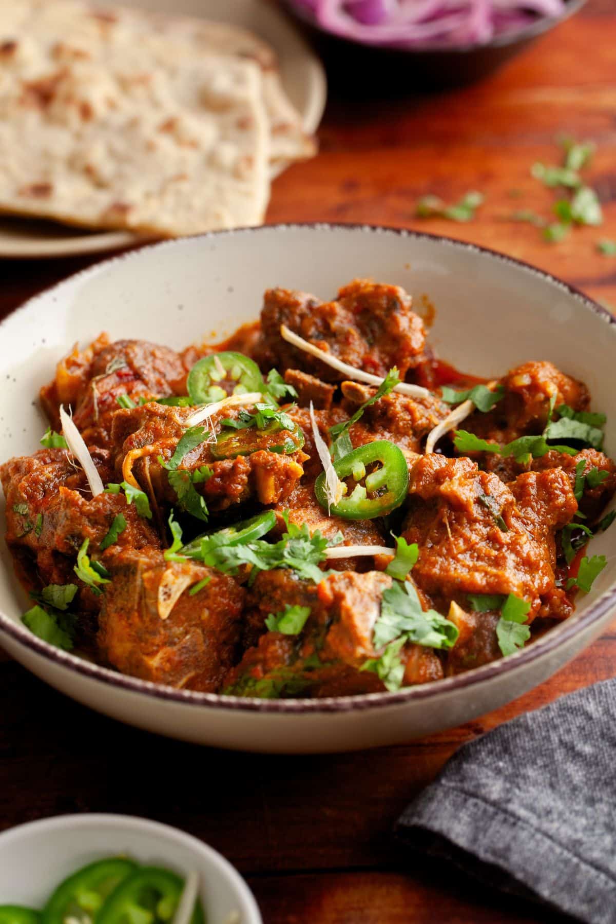 Karahi goat side image with tandoori roti in background.