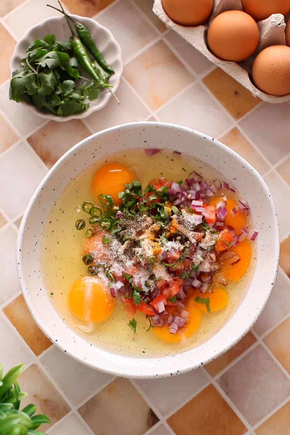Eggs in a white bowl with vegetables and spices.