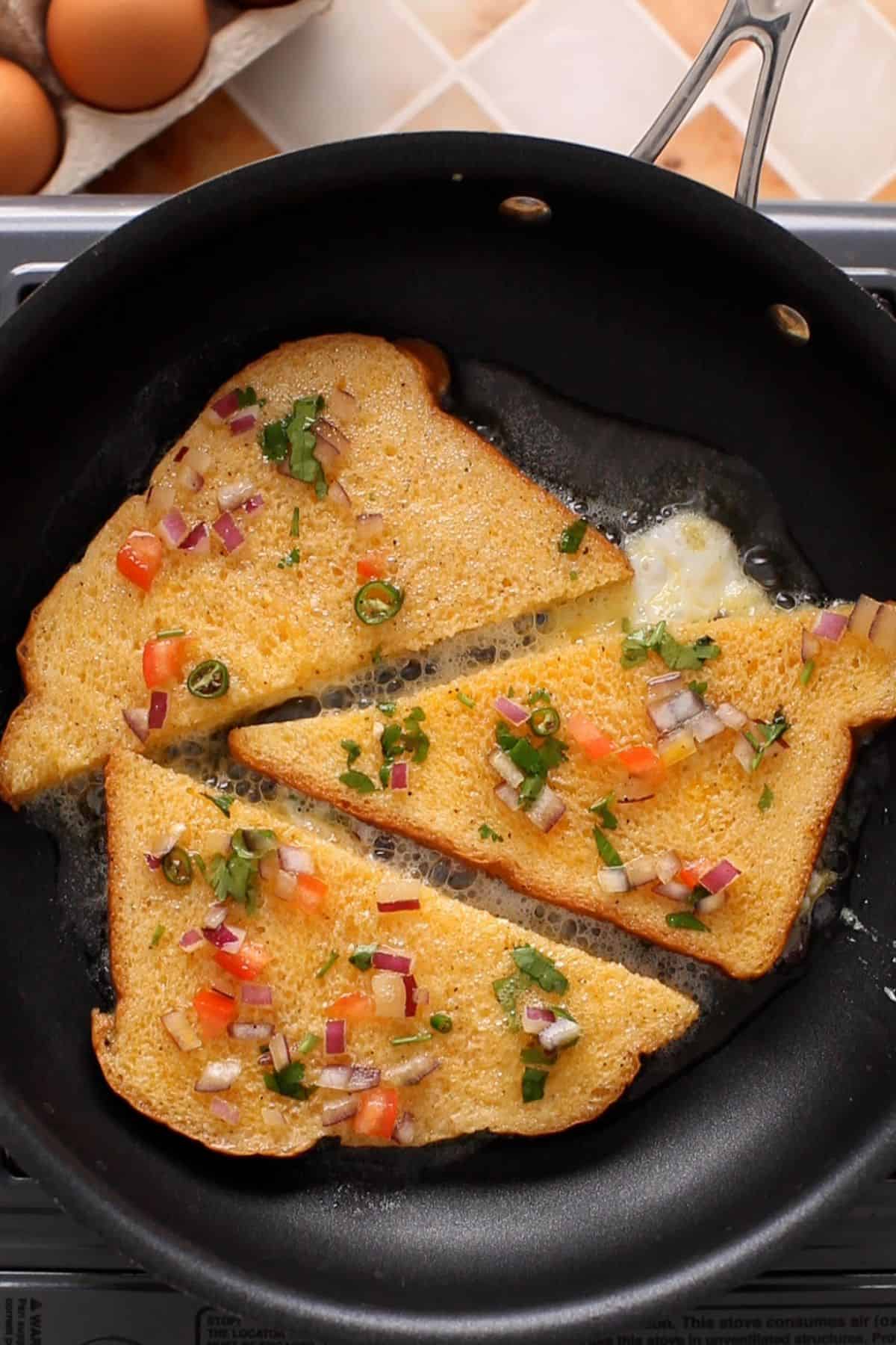 Dipped bread slices are placed on a non stick pan to cook.