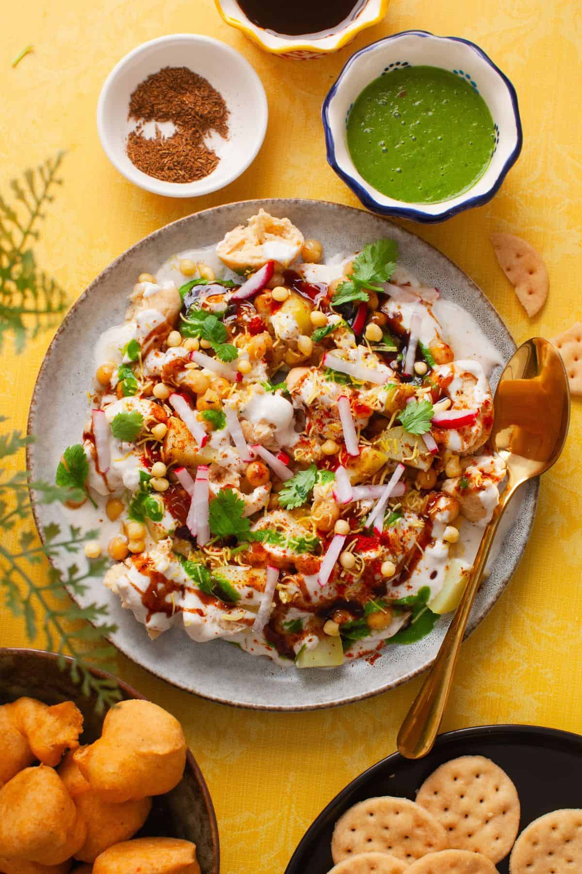 A plate of bhalla papdi chaat in an ivory plate with chaat toppings.