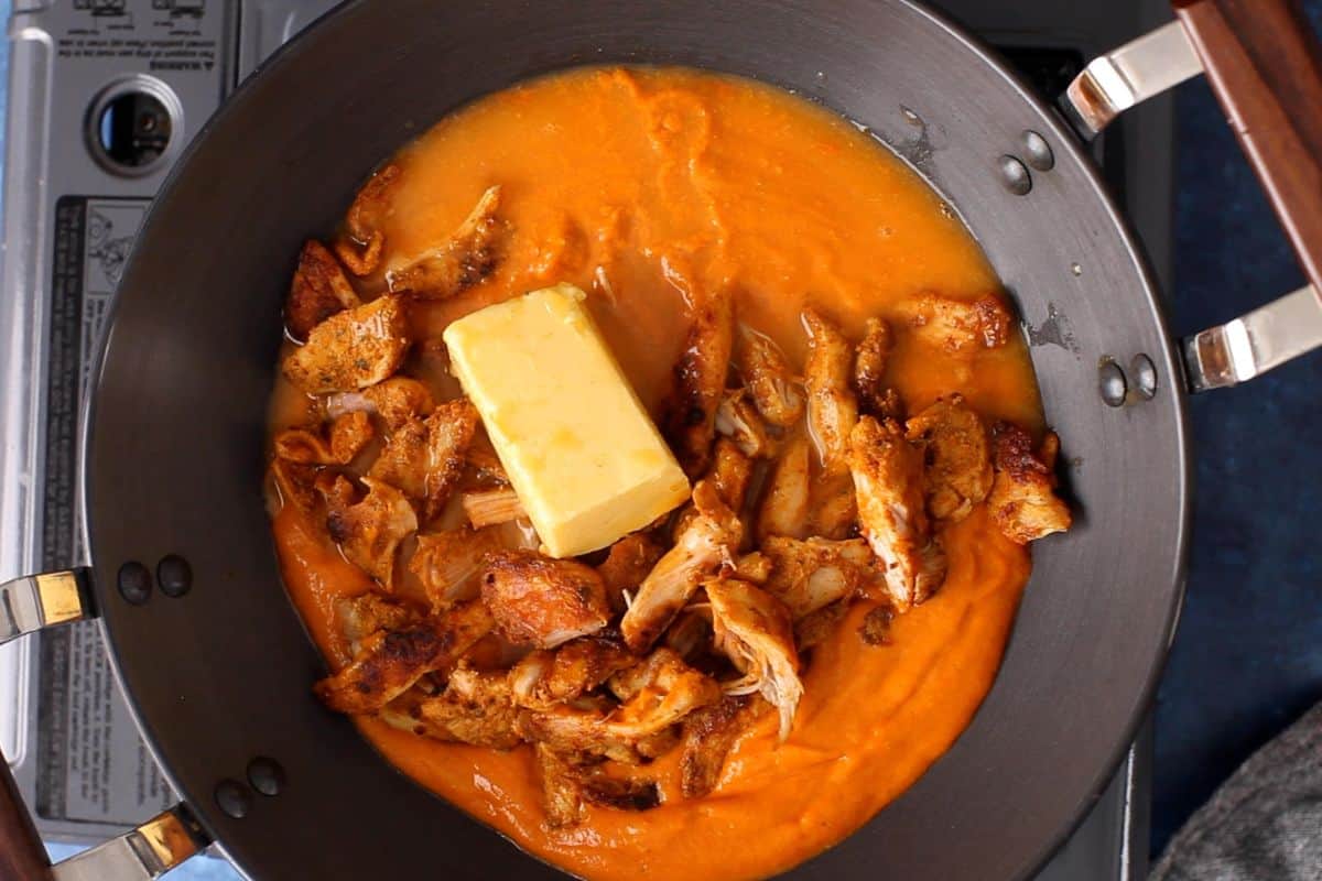 Makhani sauce, butter and tandoori chicken are combined in the cooking pot.