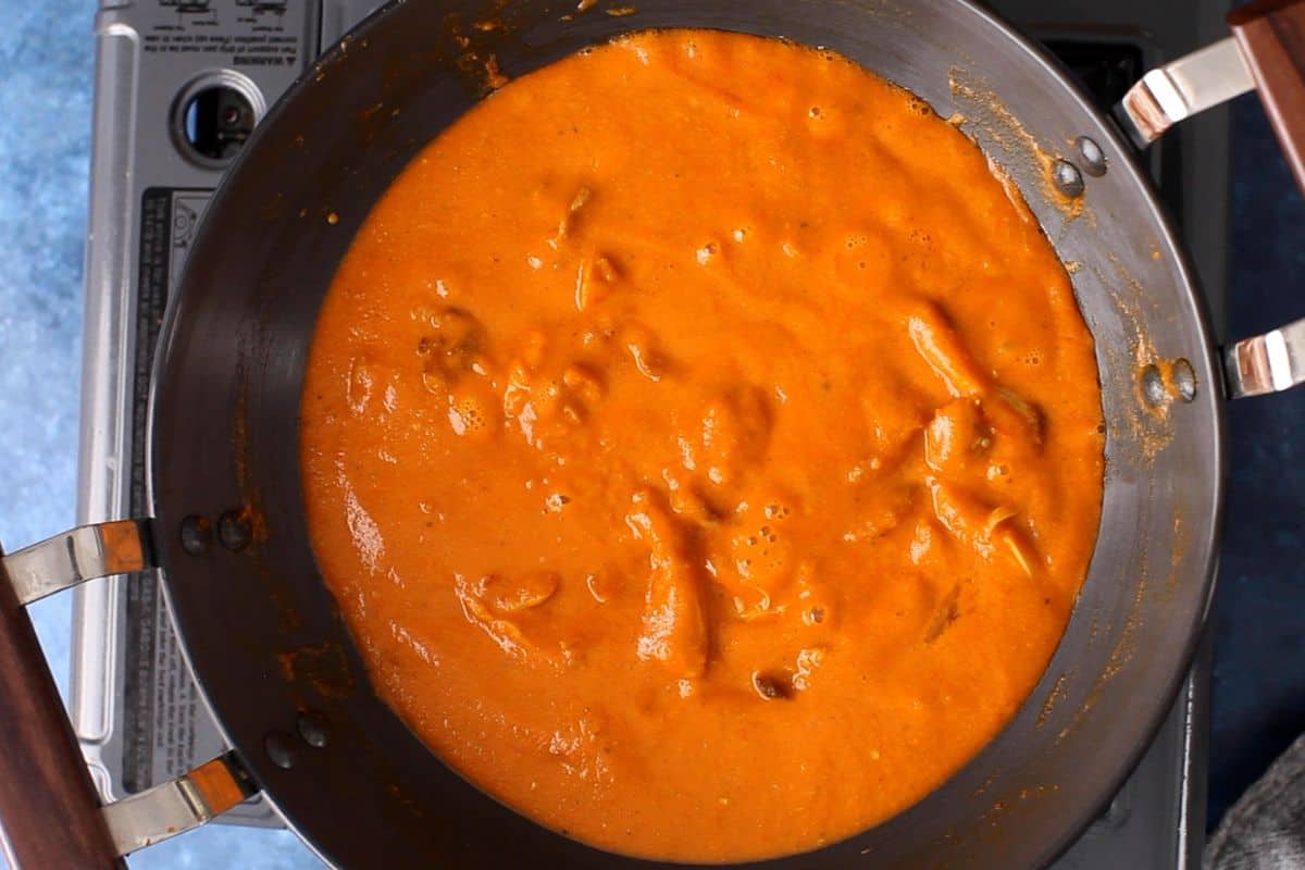 Butter chicken is simmered until small pools of butter are visible on surface.