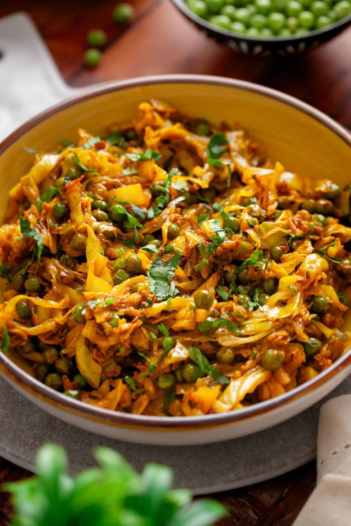 Side image of cabbage sabzi served in a yellow bowl.