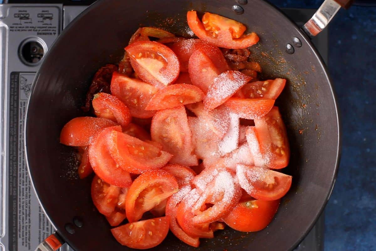 Sliced tomatoes are added and sprinkled with salt and sugar. 
