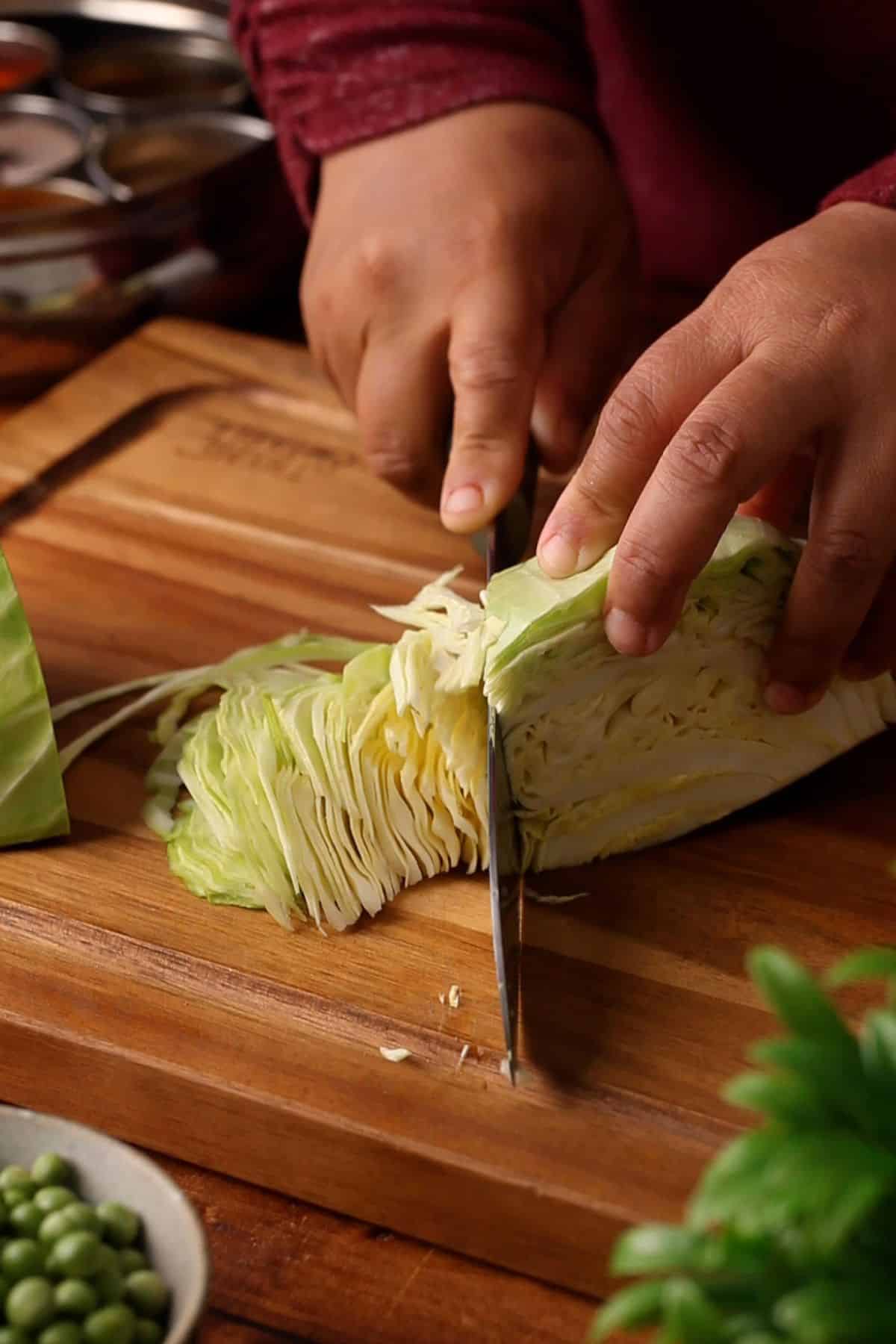 Shredding a cabbage on a wooden cutting board.