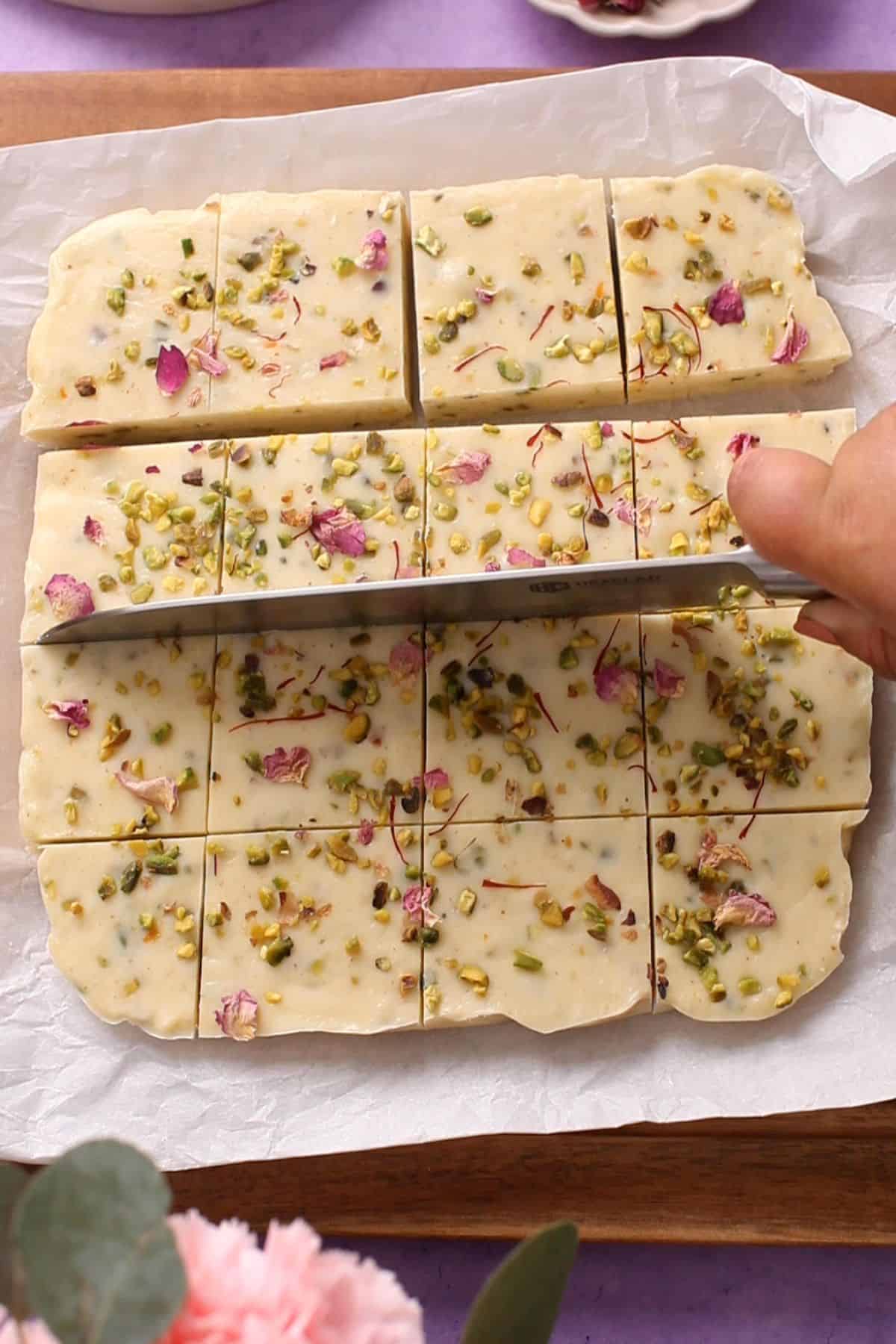 Cutting thandai fudge with knife.
